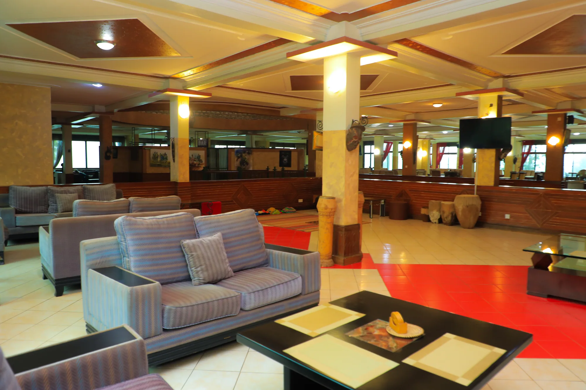 A hotel lobby lounge with grey sofas, a central pillar and a red patterned floor