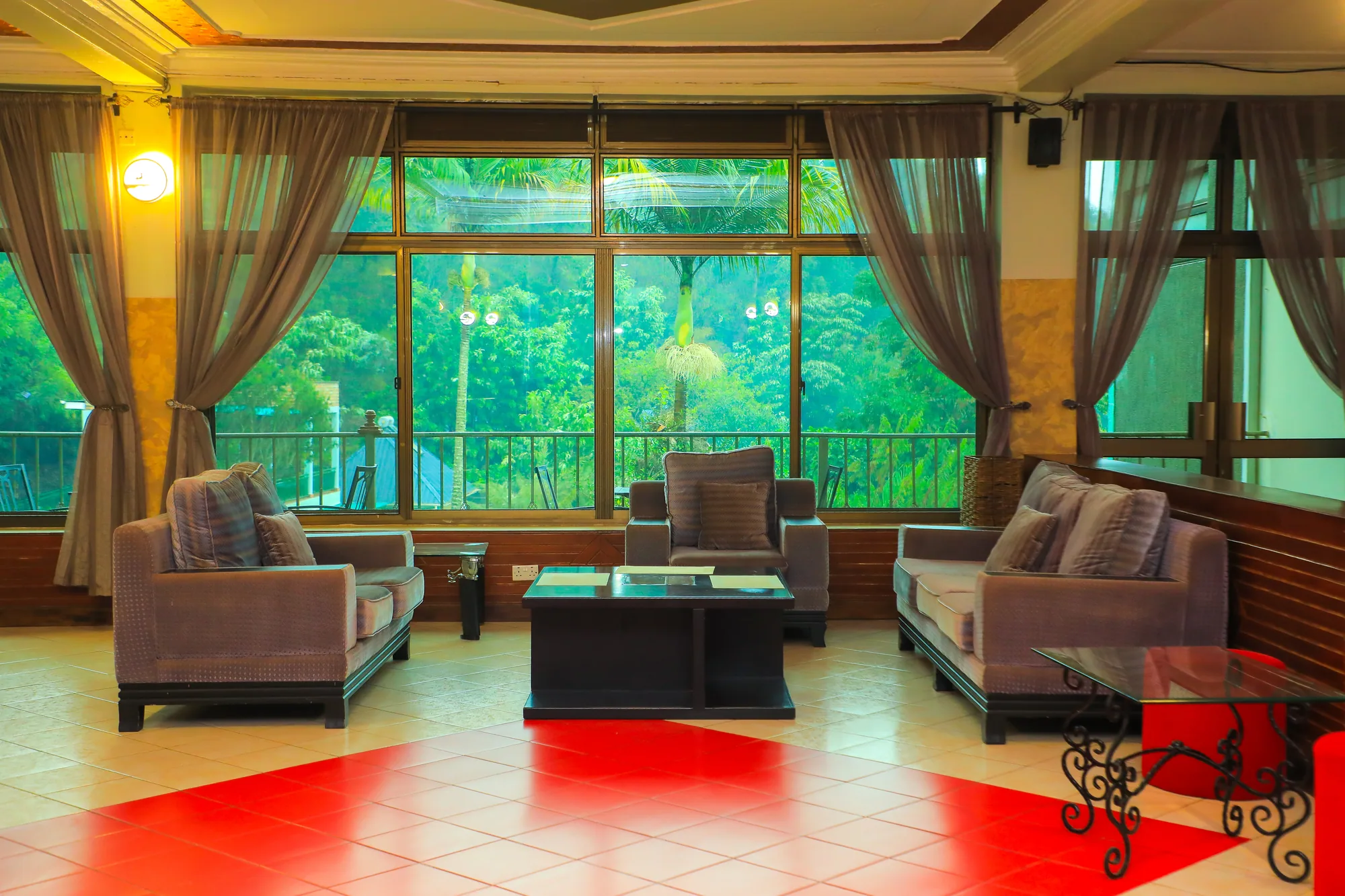 A lounge with two grey armchairs and a low table in front of curtained lake-facing windows