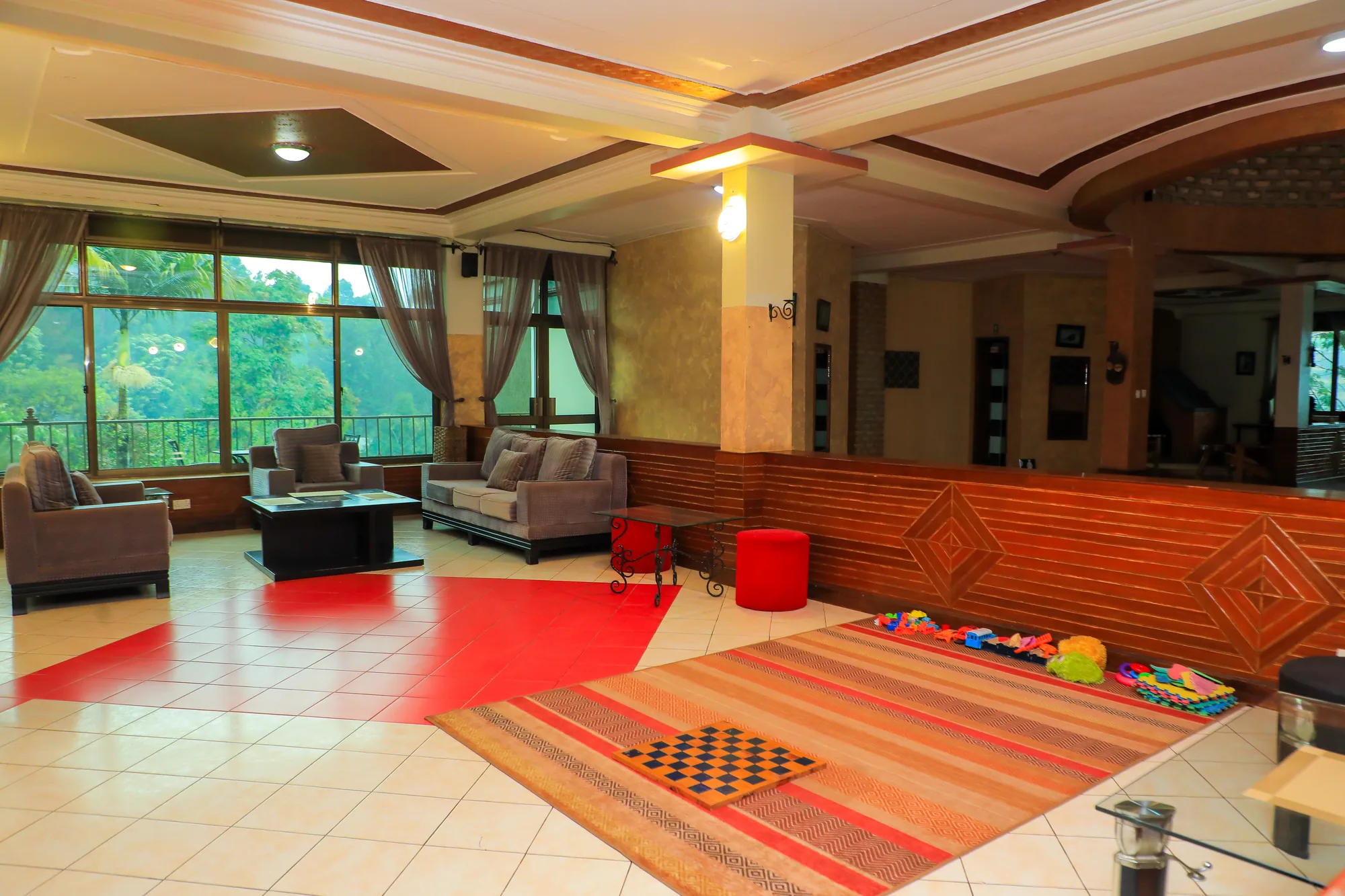 A lounge and children's play corner with sofas, a rug and a draughts mat on the floor