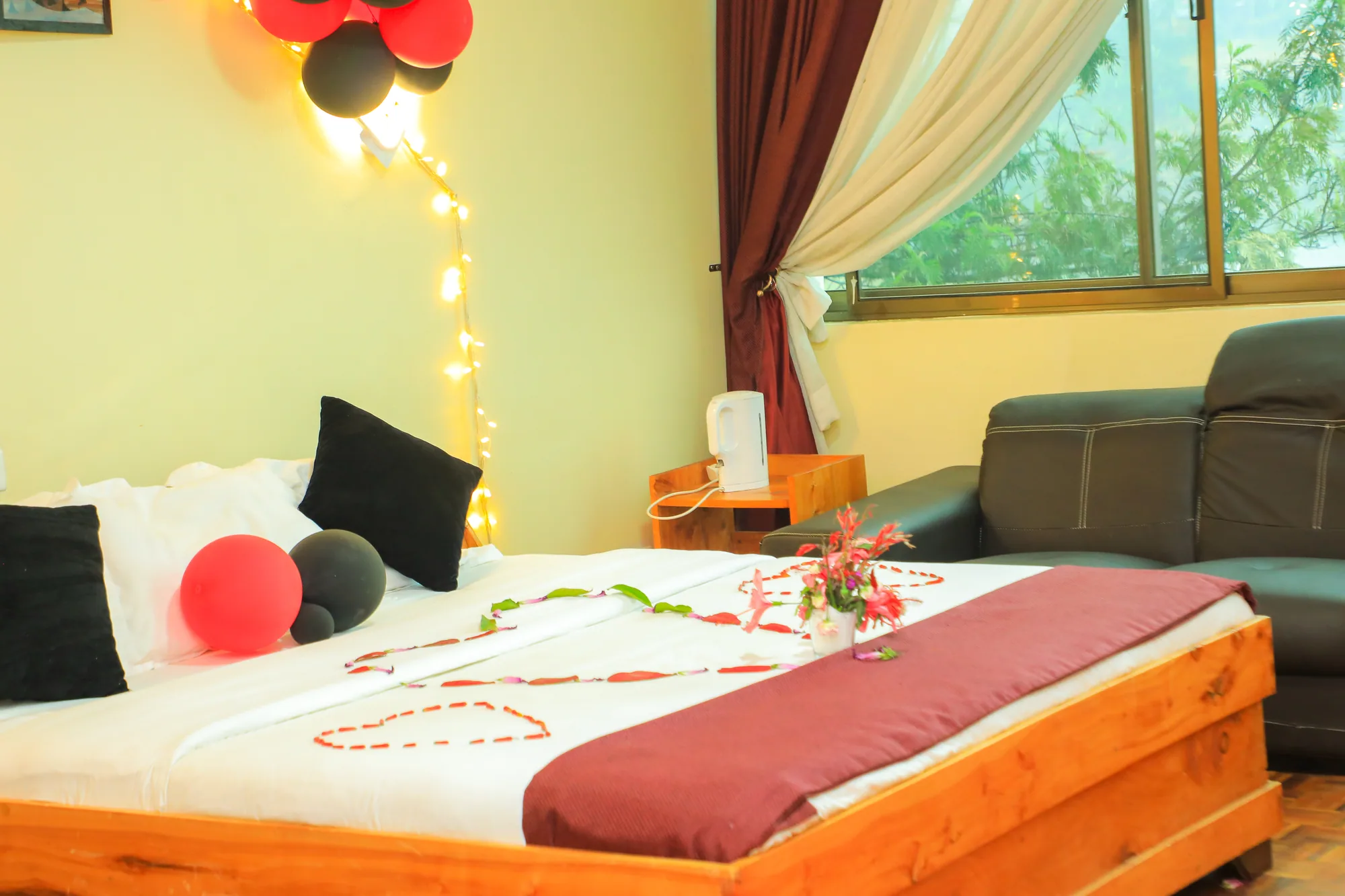 Deluxe Triple Room: bed dressed with a red runner and rose-petal heart, with fairy lights above the headboard