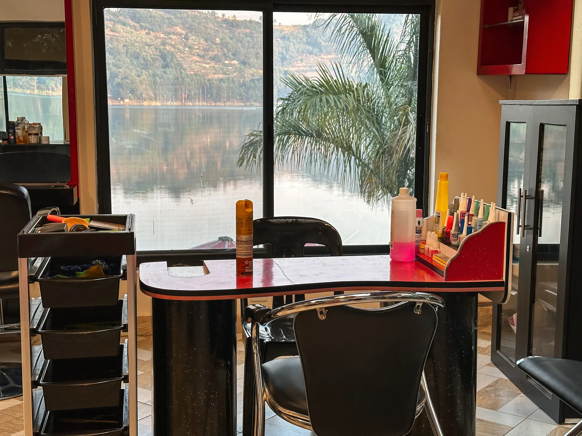 A café table and stools beside the tall windows looking onto the lake