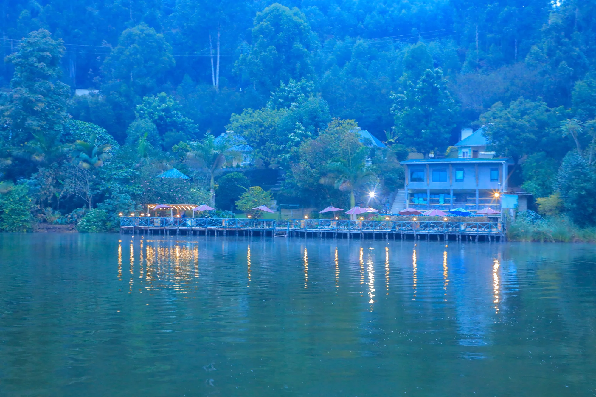 The resort's lit lakeside decks reflected in the water in blue evening light