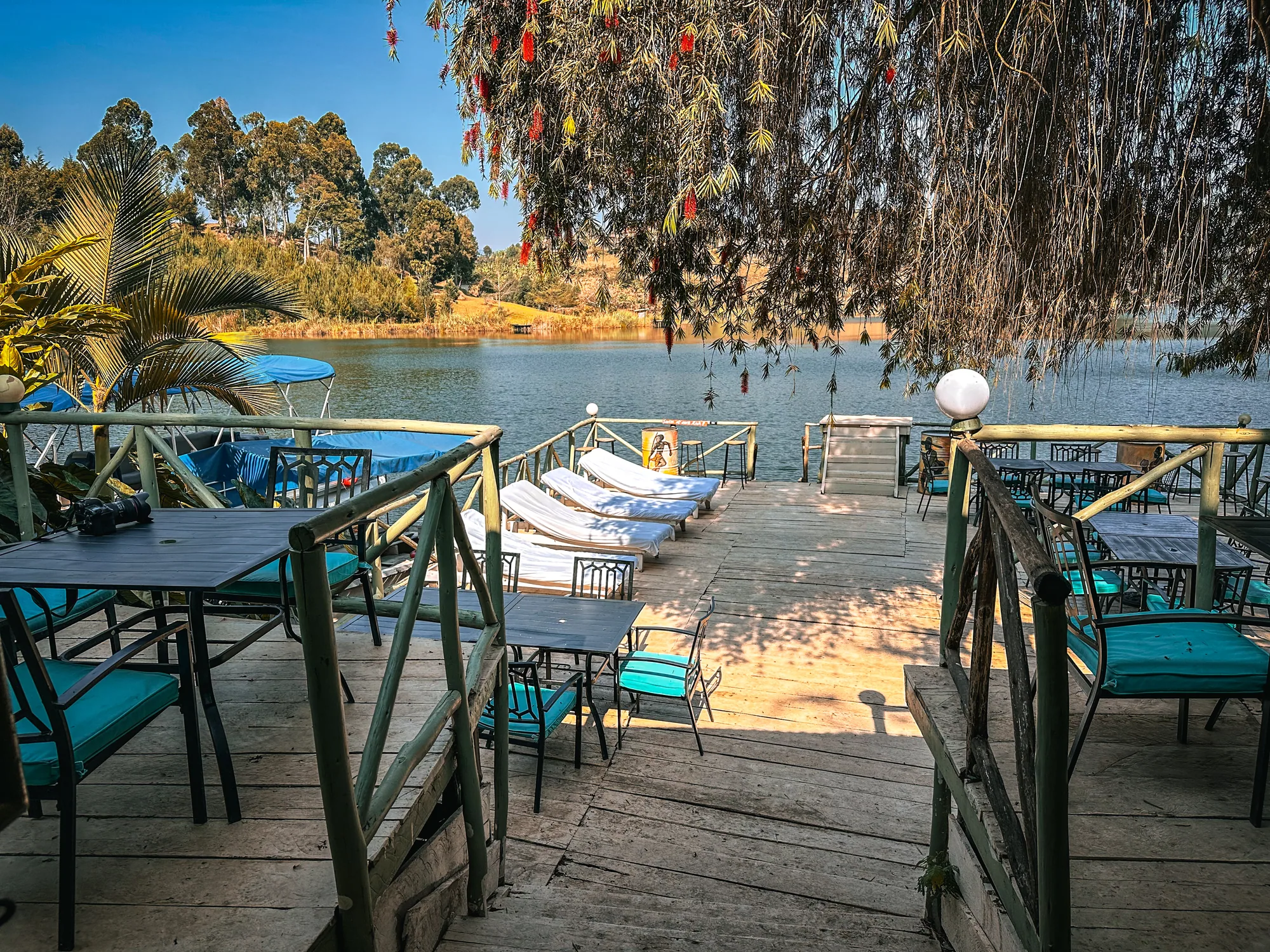 The jetty deck with sun loungers and tables under an overhanging tree