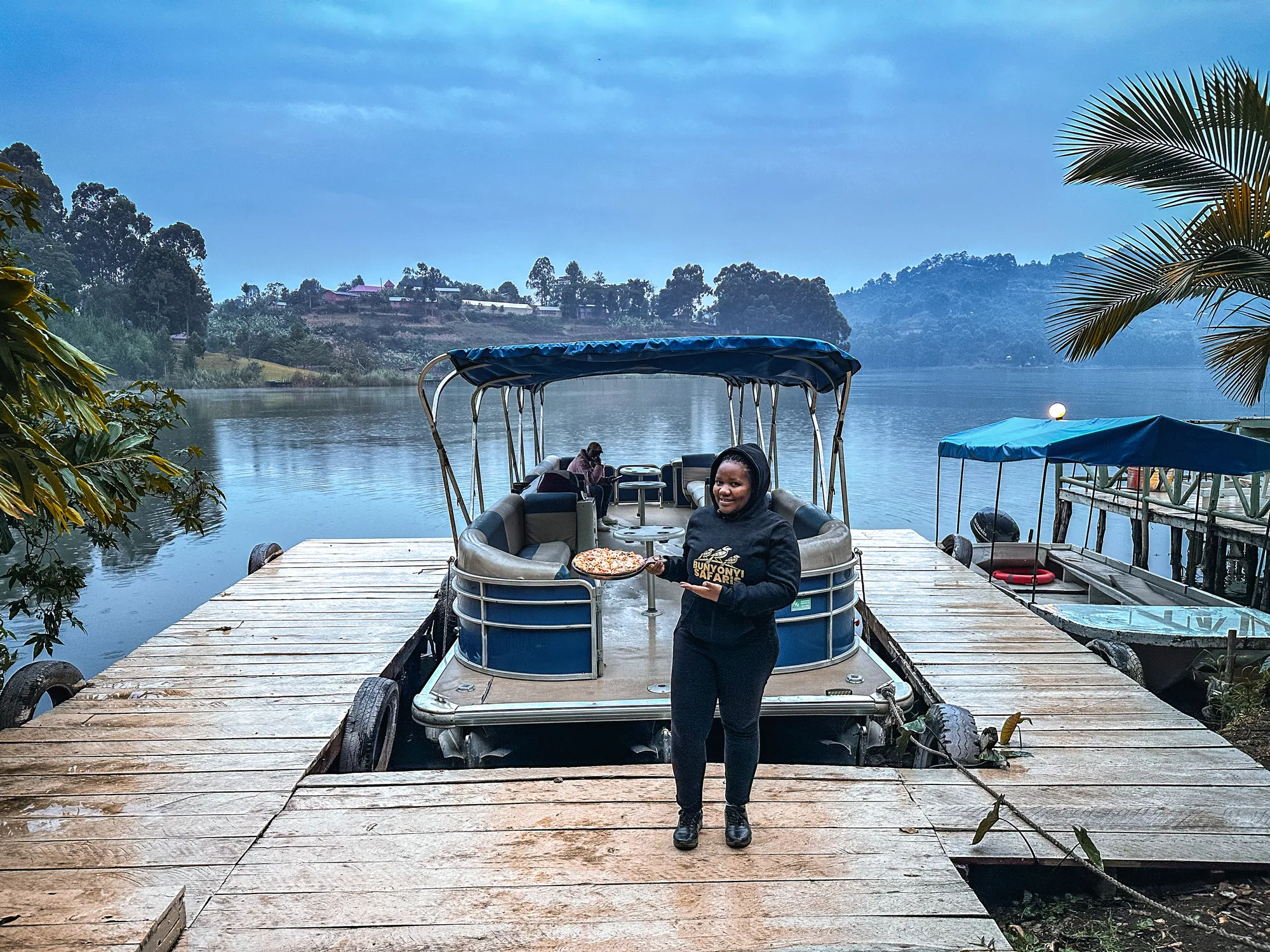 A staff member standing on the jetty in front of a moored canopied cruise boat