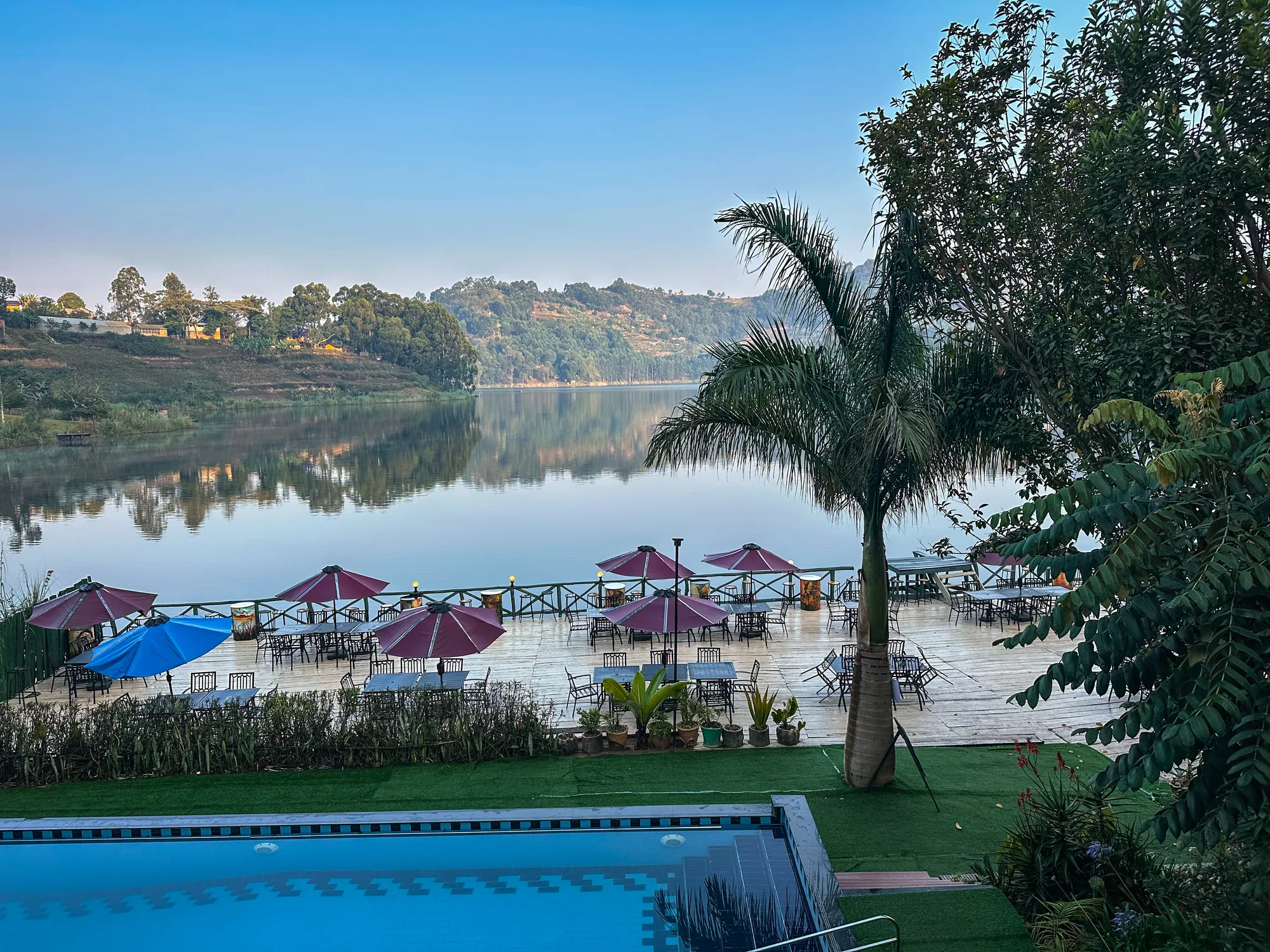 The lake at first light with pink parasols on the deck and the pool in the foreground