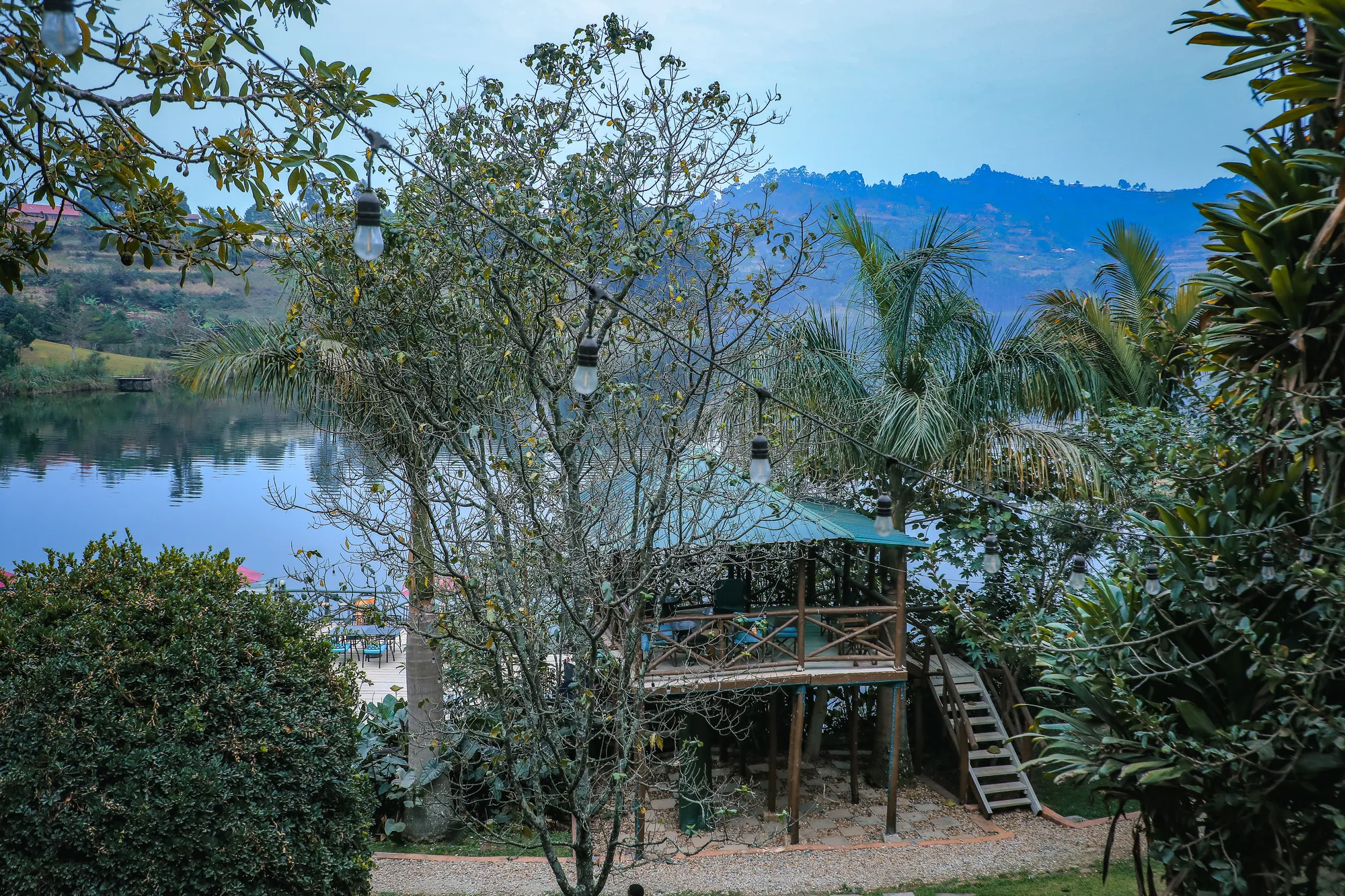 The tree-house platform among garden shrubs with the lake and hills behind