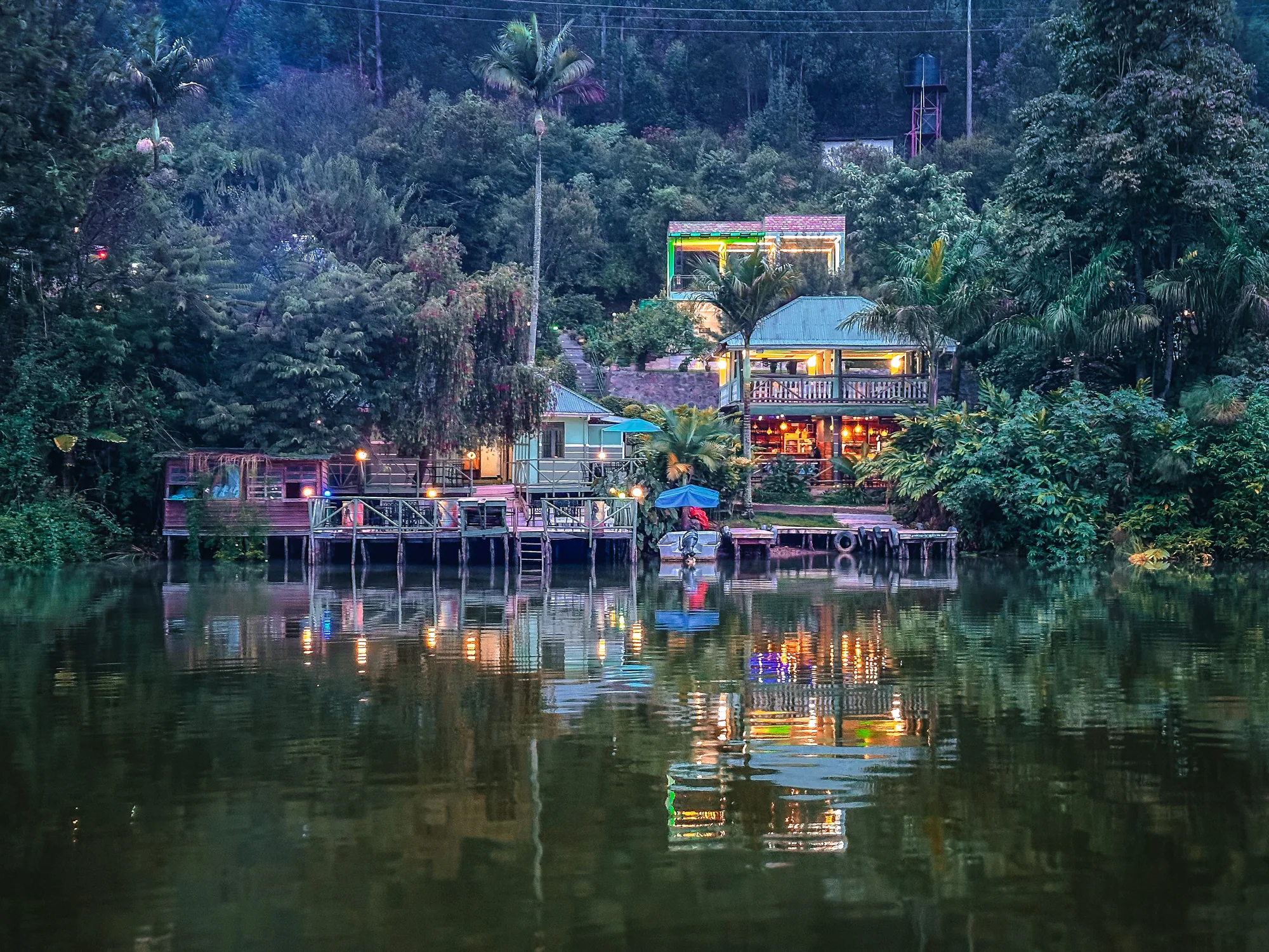 The resort's decks and buildings lit in colour at night, mirrored in the water