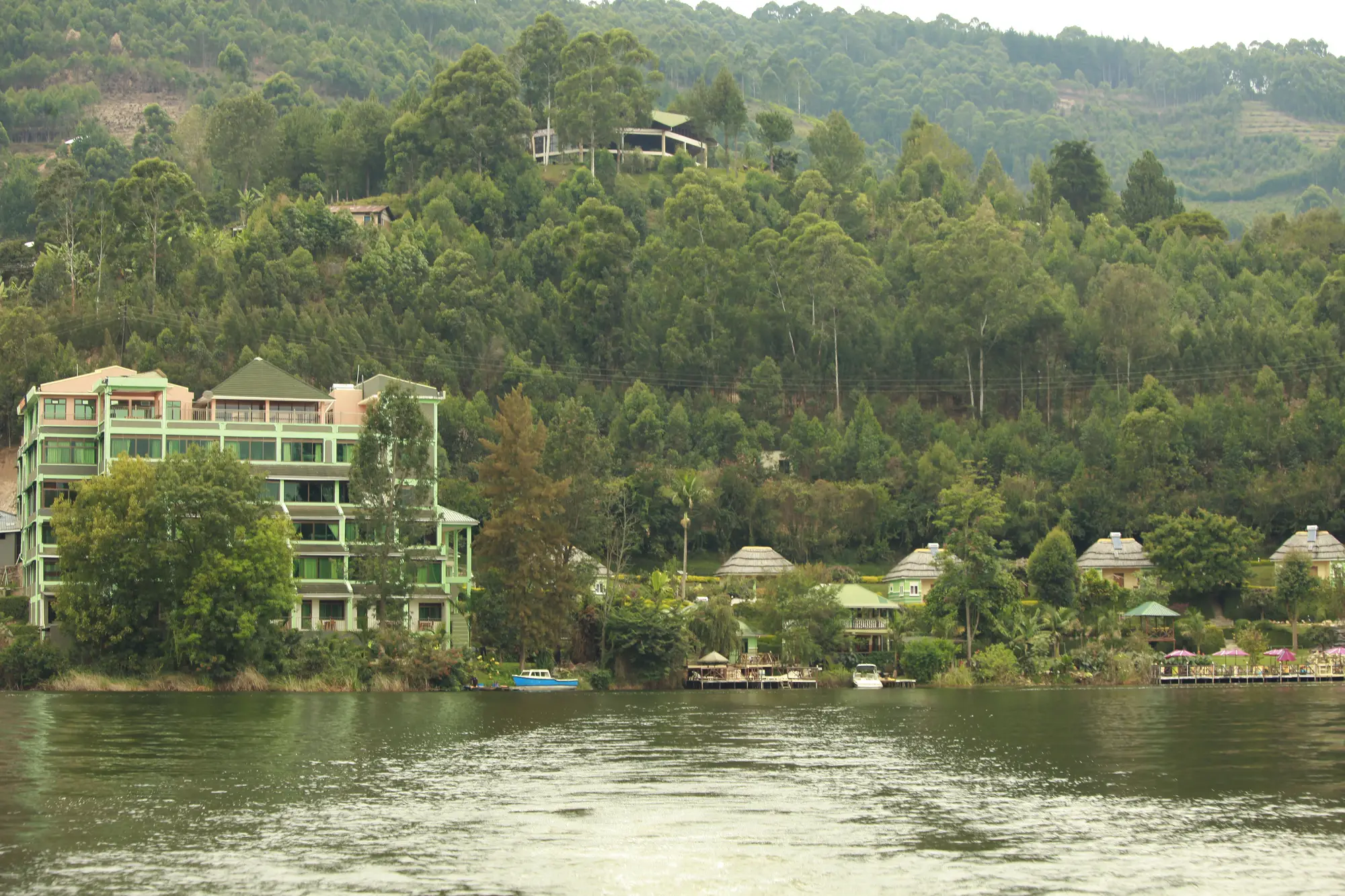 The resort seen from the water: hotel block, thatched gazebos and the shoreline hedge