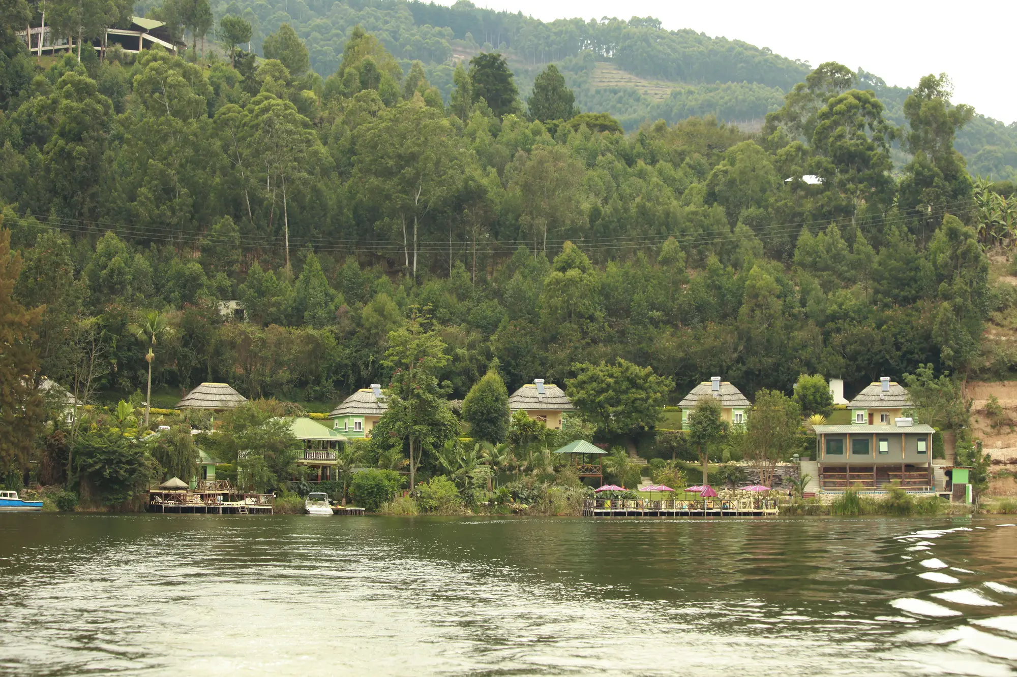 The thatched lakeside gazebos in a row along the shore, seen from a boat