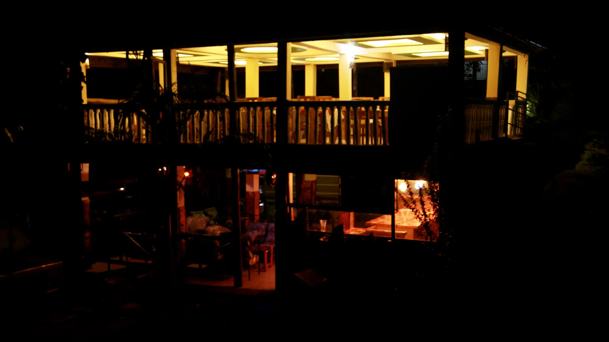 Two-storey open wooden pavilion lit at night