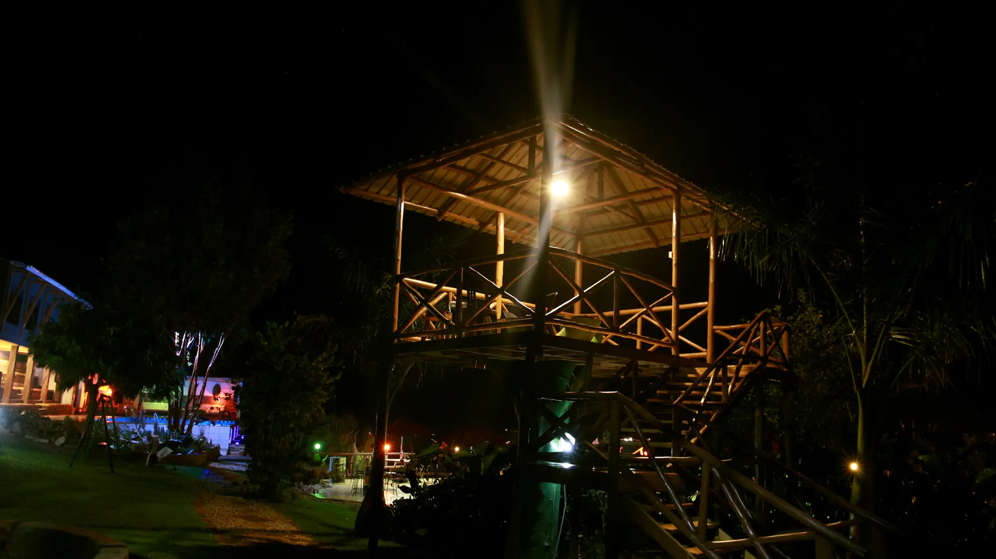 Thatched lakeside pavilion lit at night