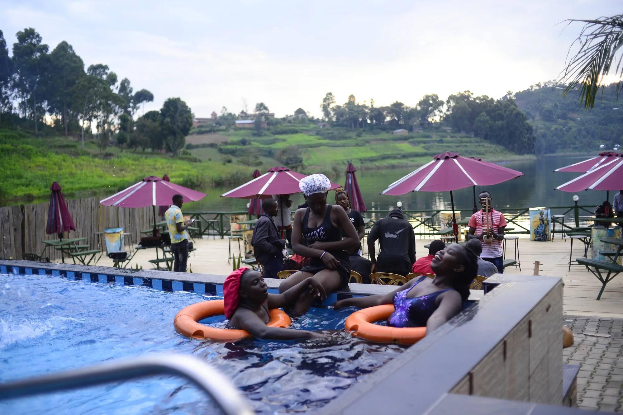 Guests sitting on the pool edge with orange rings under pink parasols
