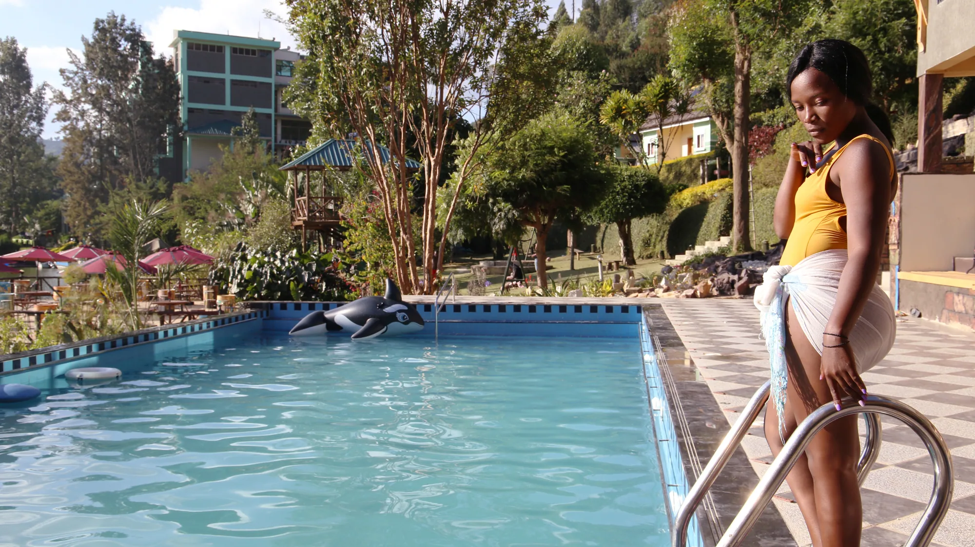 A guest holding the pool ladder rail at the shallow end in the daytime