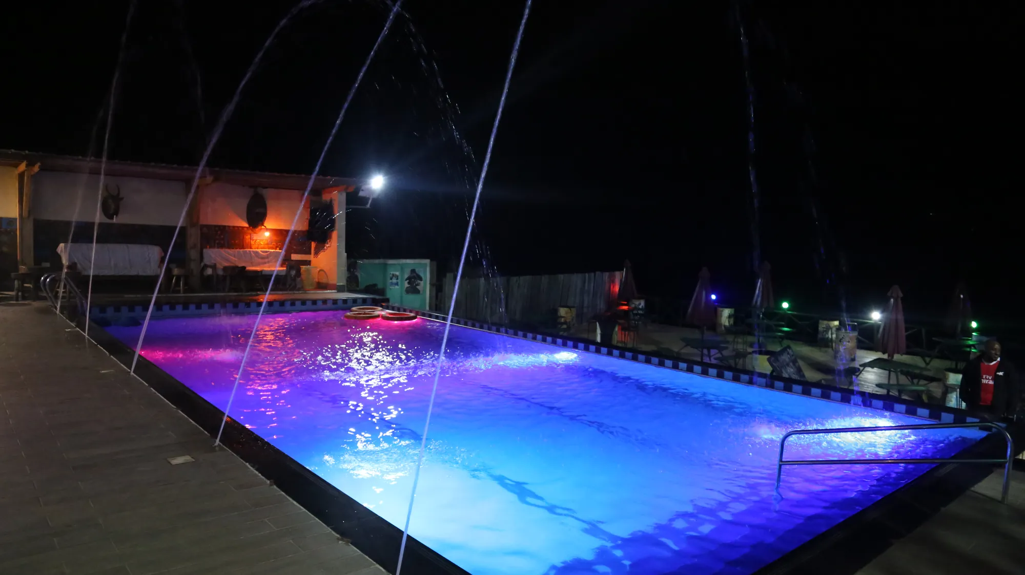 The pool lit purple and blue at night with its jets running
