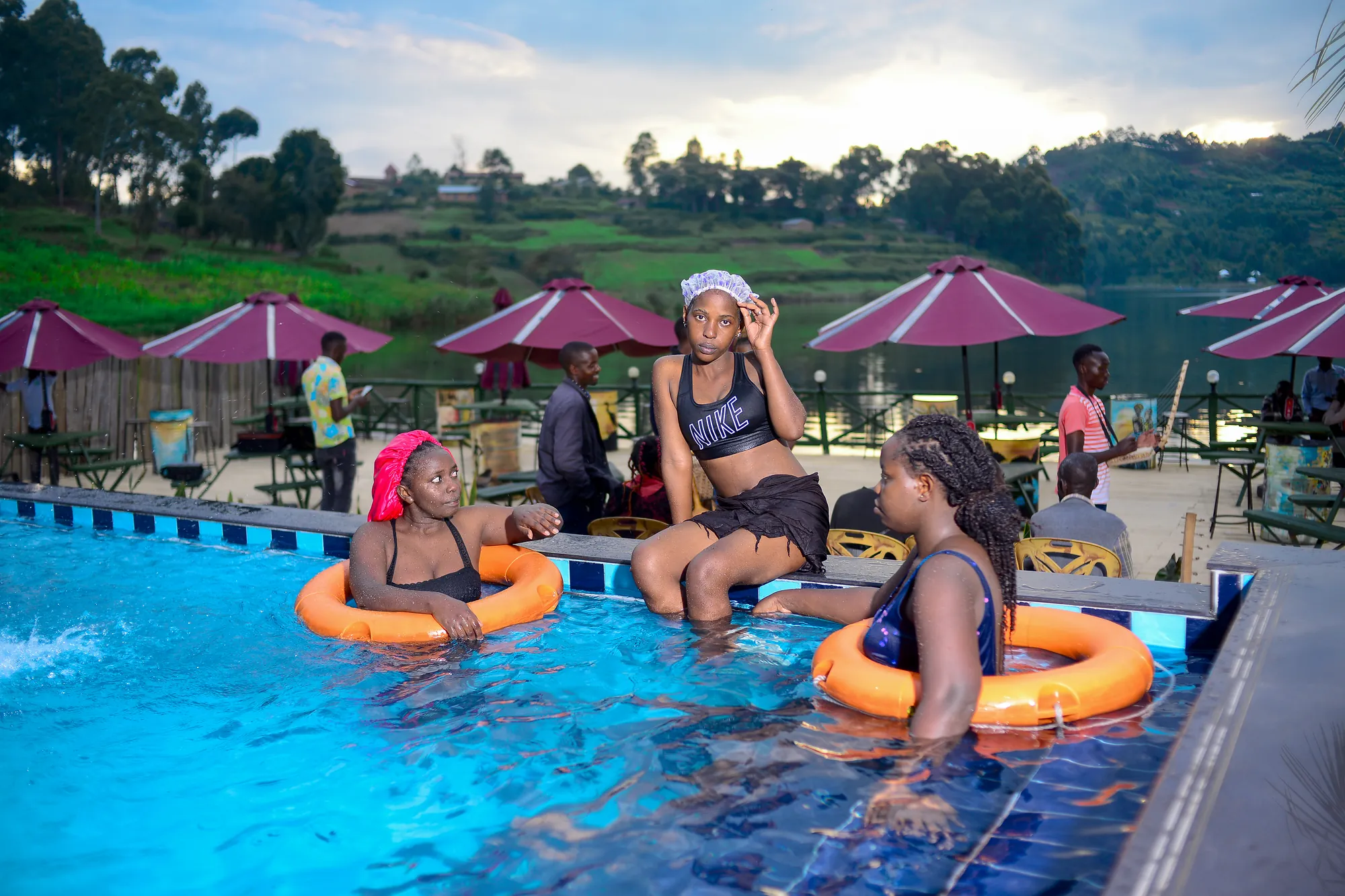 Four guests floating on rings in the pool with pink parasols behind