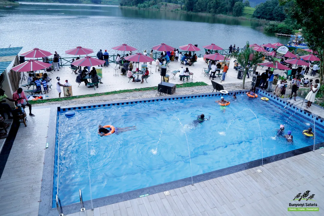 A busy pool with swimmers and guests seated under pink parasols on the terrace