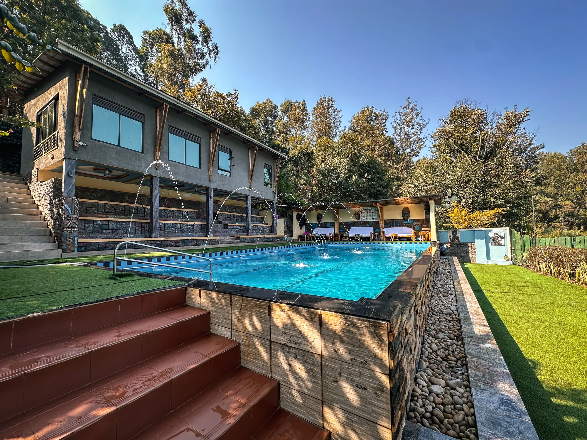 The pool and its stone-edged lawn below the timber-fronted rooms
