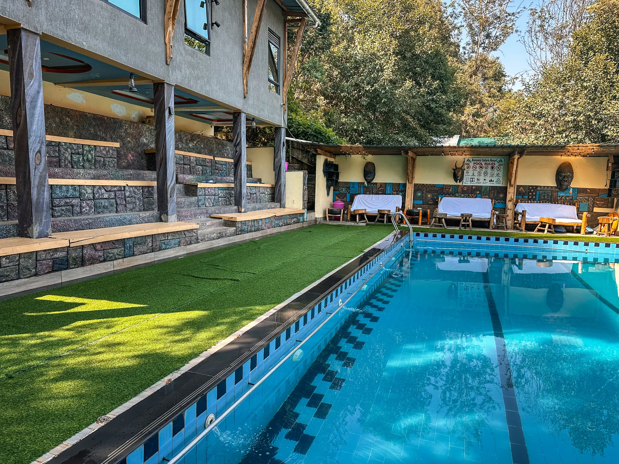 The pool along the lawn with the bar terrace and loungers alongside