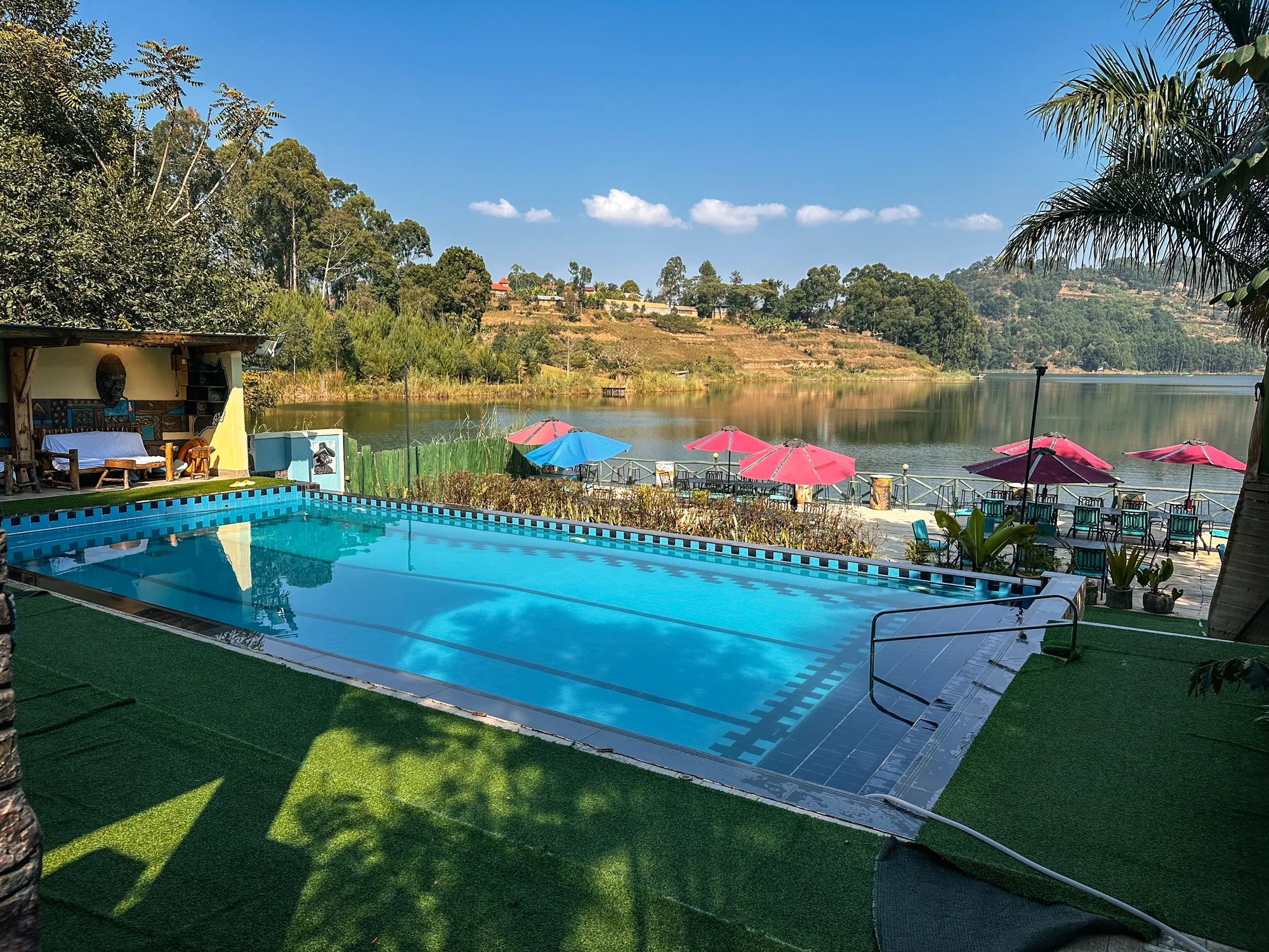 The pool and lakeside deck with pink parasols and the hills across the water