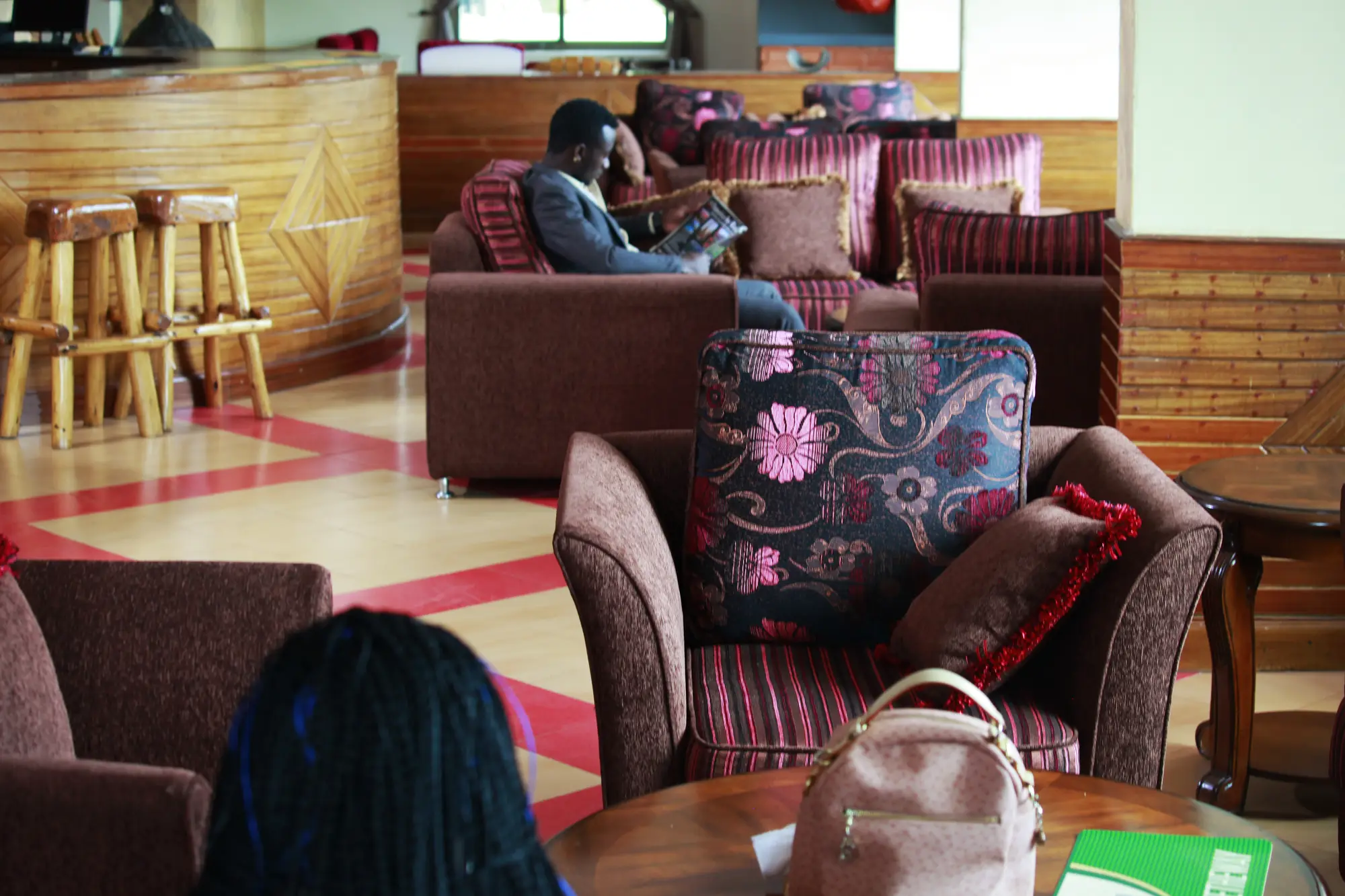 Guest seated in the lounge among upholstered armchairs and carved wooden stools