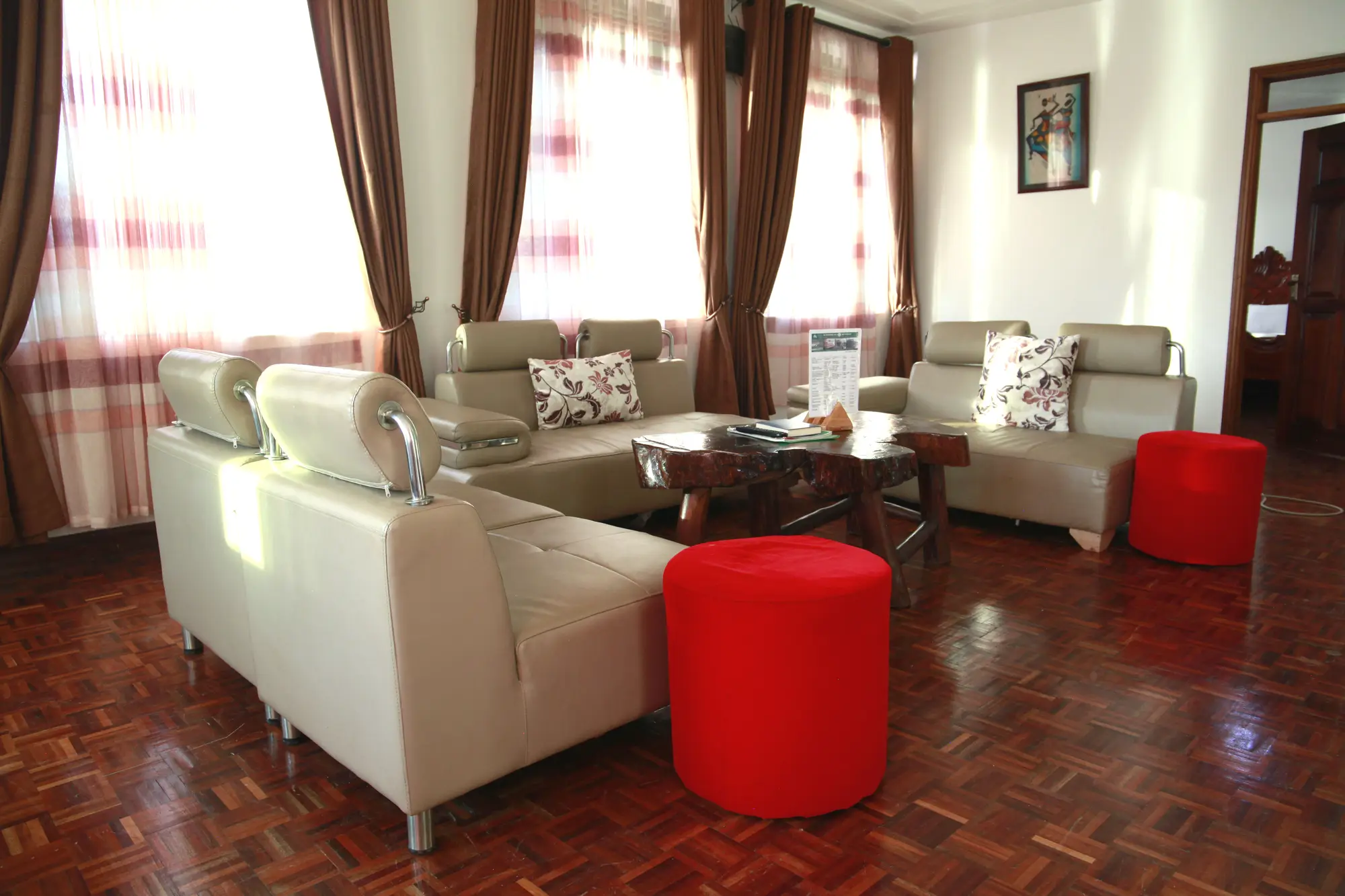 Sitting room with cream sofas, a red ottoman and a parquet floor
