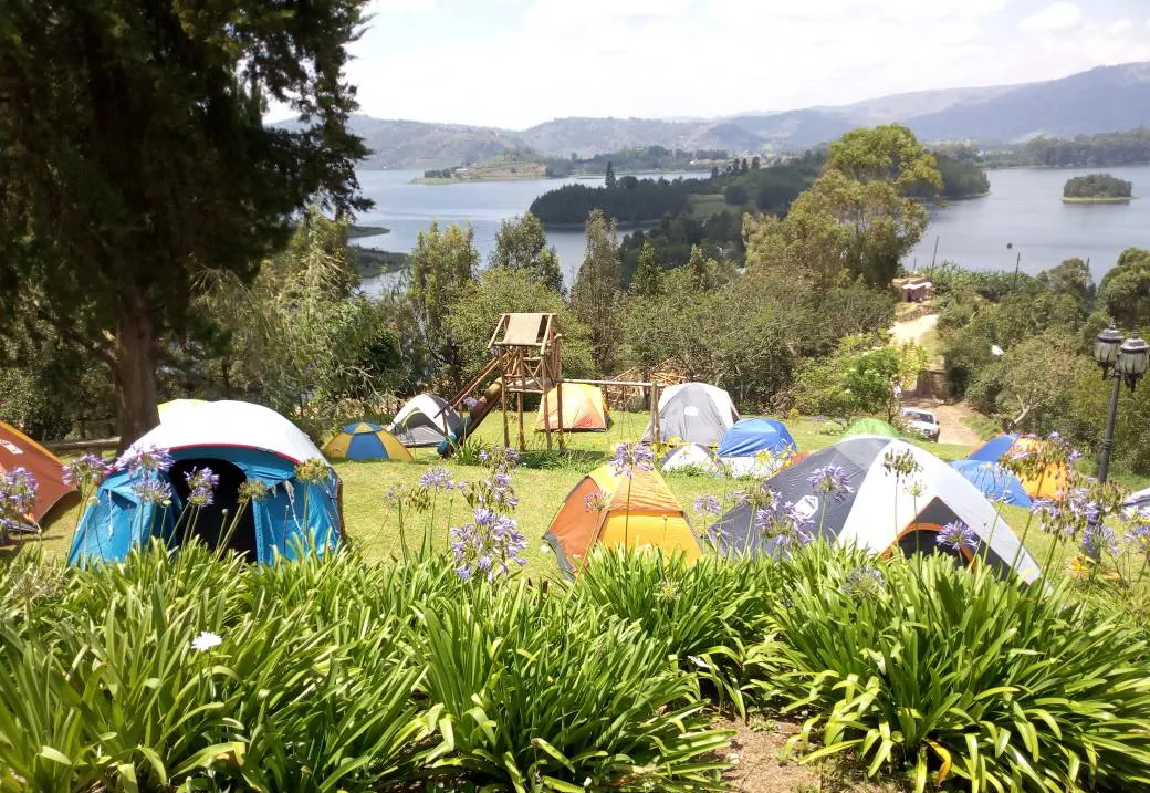 Tents pitched on the camping lawn above the lake, with a play frame behind