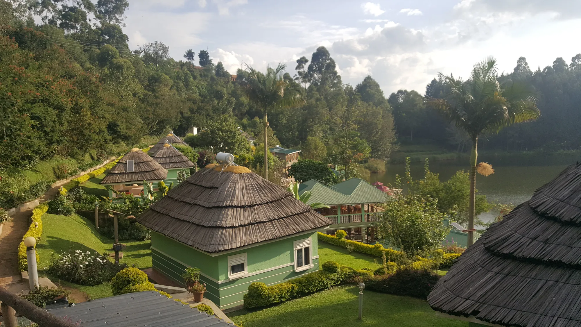 Thatched and green-roofed cottages among lawns and hedges above the lake
