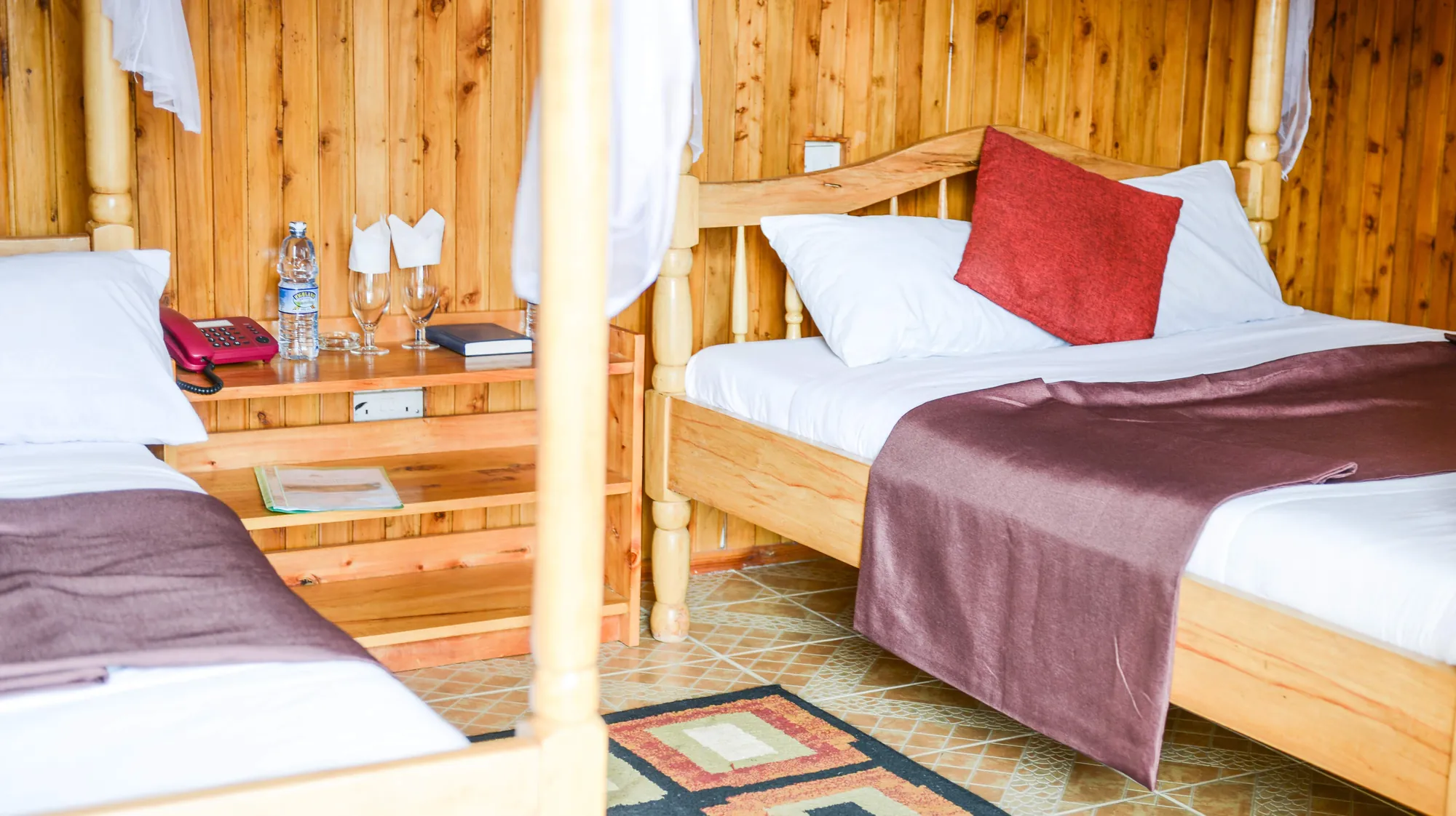 Double / Twin Room: two single beds with mosquito nets and maroon throws in a panelled twin room