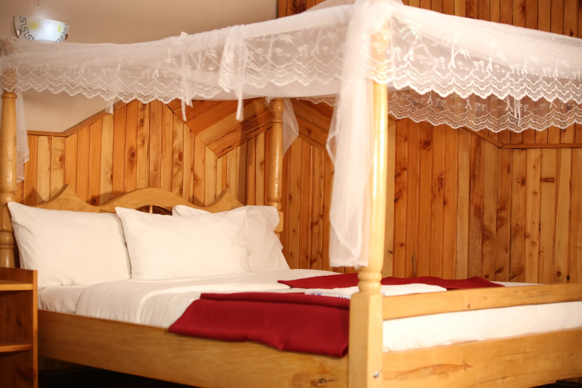 Double / Twin Room: four-poster bed with a mosquito net and a red runner in a timber-panelled room