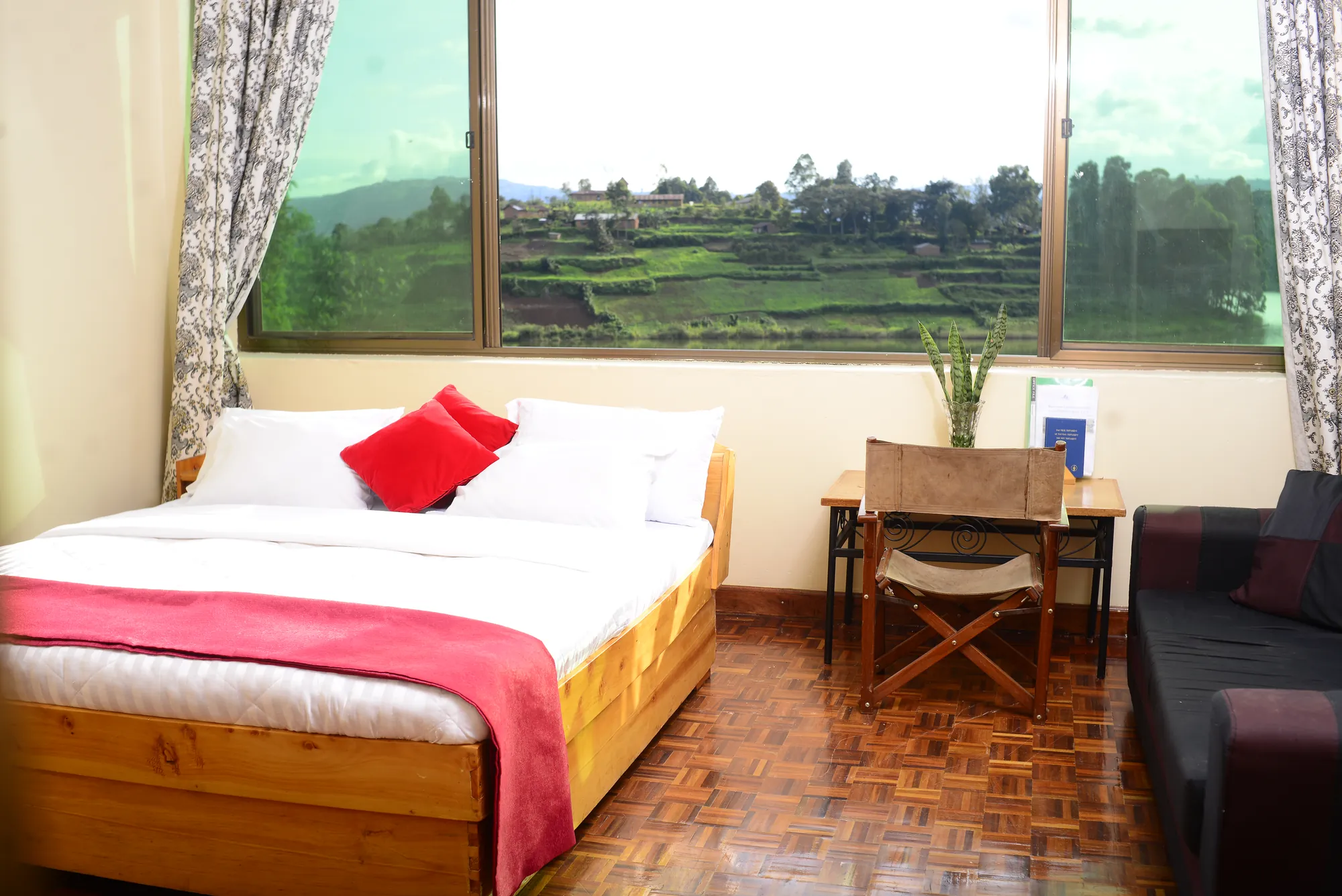 Double / Twin Room: bed with a red runner beside a wide window looking onto terraced hillsides