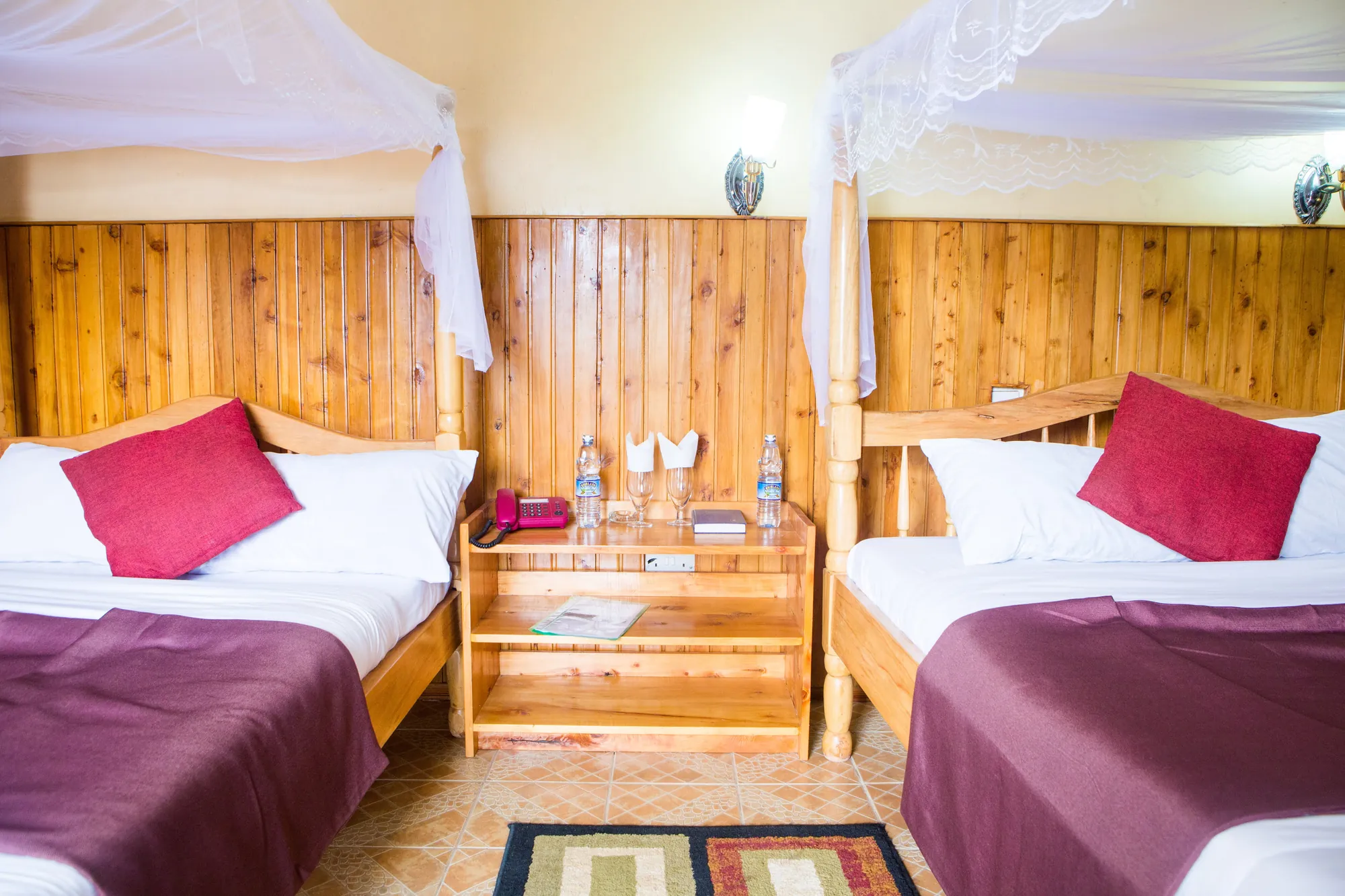 Double / Twin Room: two beds with maroon throws and pink cushions either side of a shared timber headboard