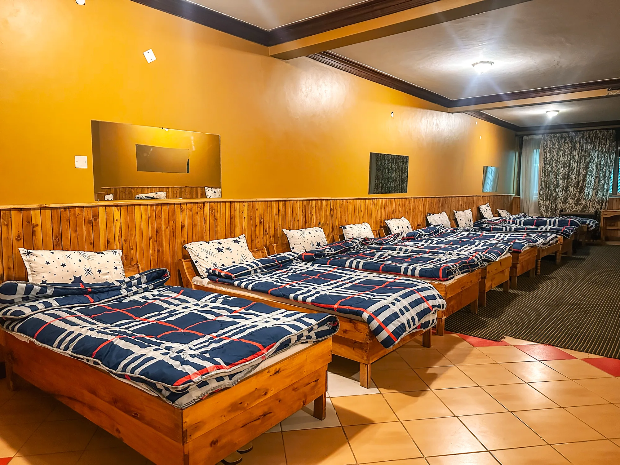 Dormitory: dormitory with single beds along a yellow wall under a wall-mounted screen