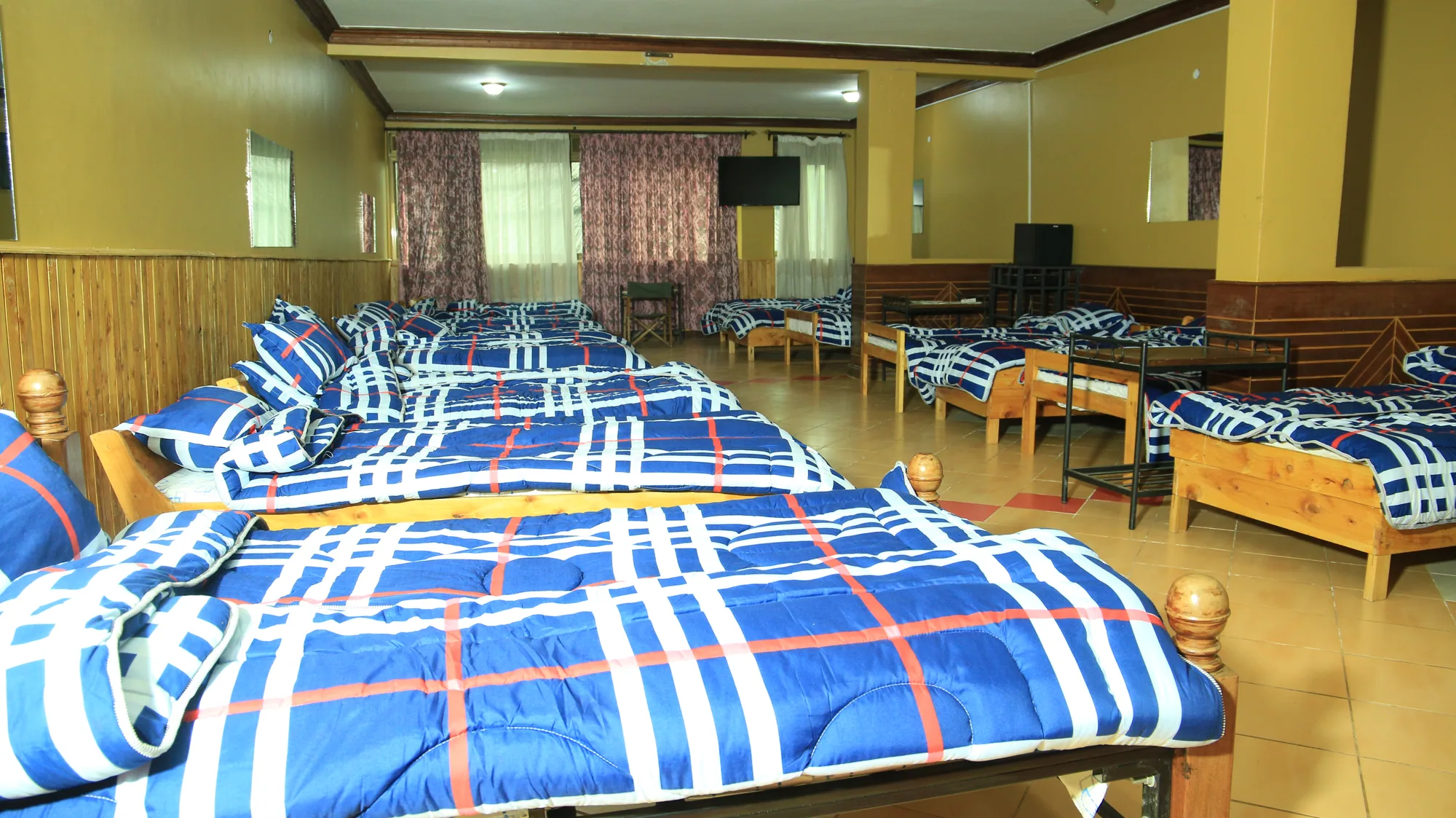 Dormitory beds seen from the doorway, the room running away to the far windows