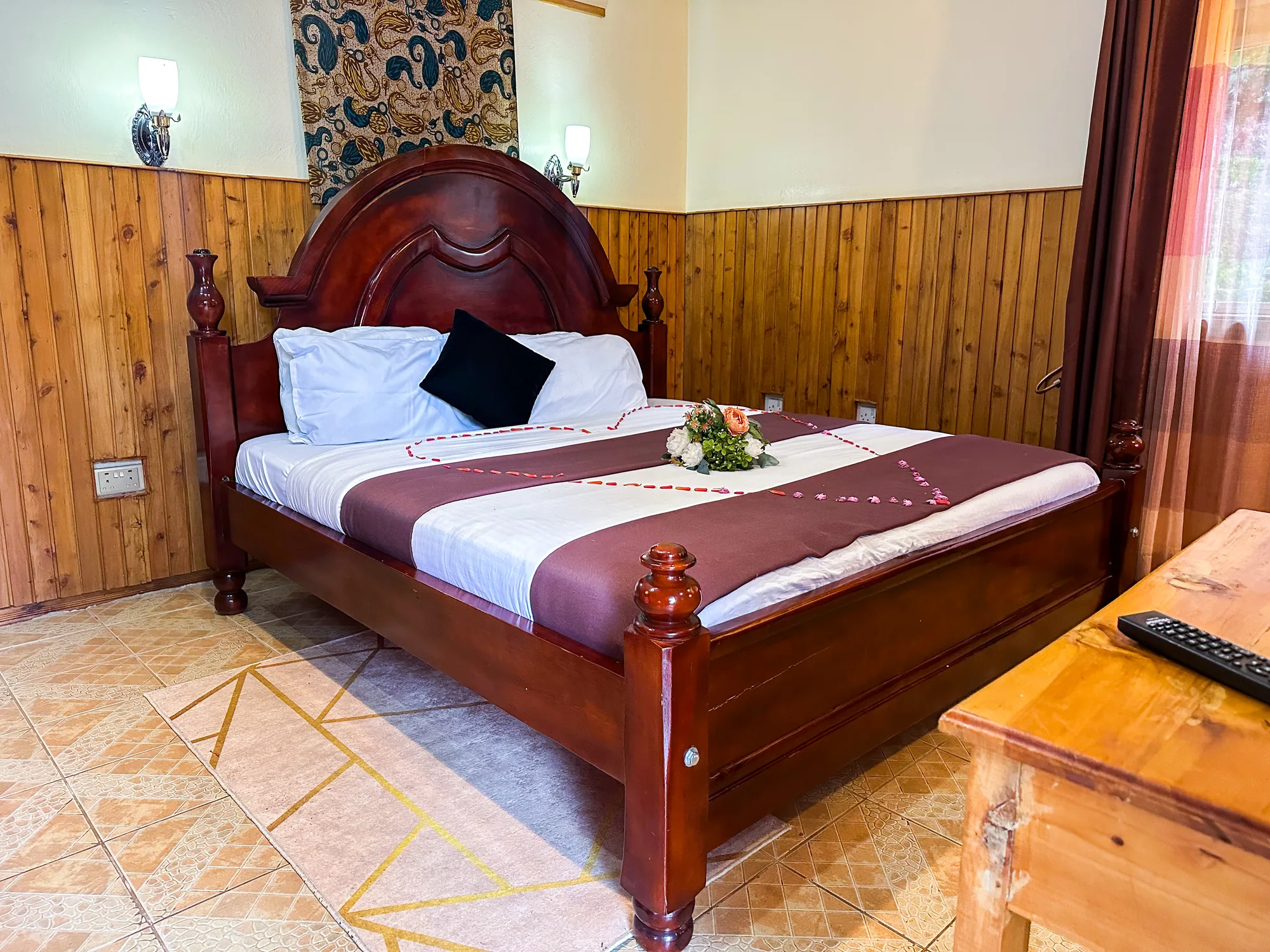 Cottage: carved wooden bed with a maroon runner beside a desk in a panelled room