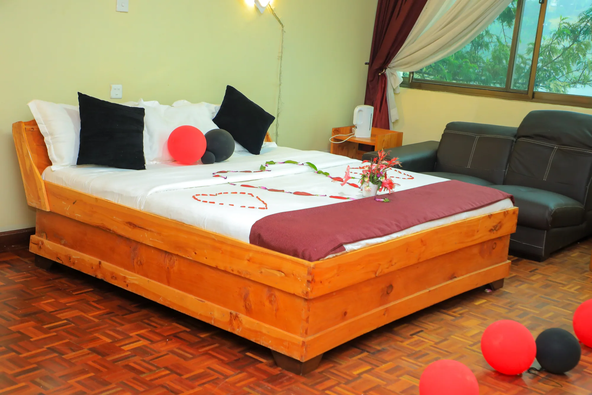 Deluxe Triple Room: bed decorated with petals and red balloons, a sofa alongside under the window