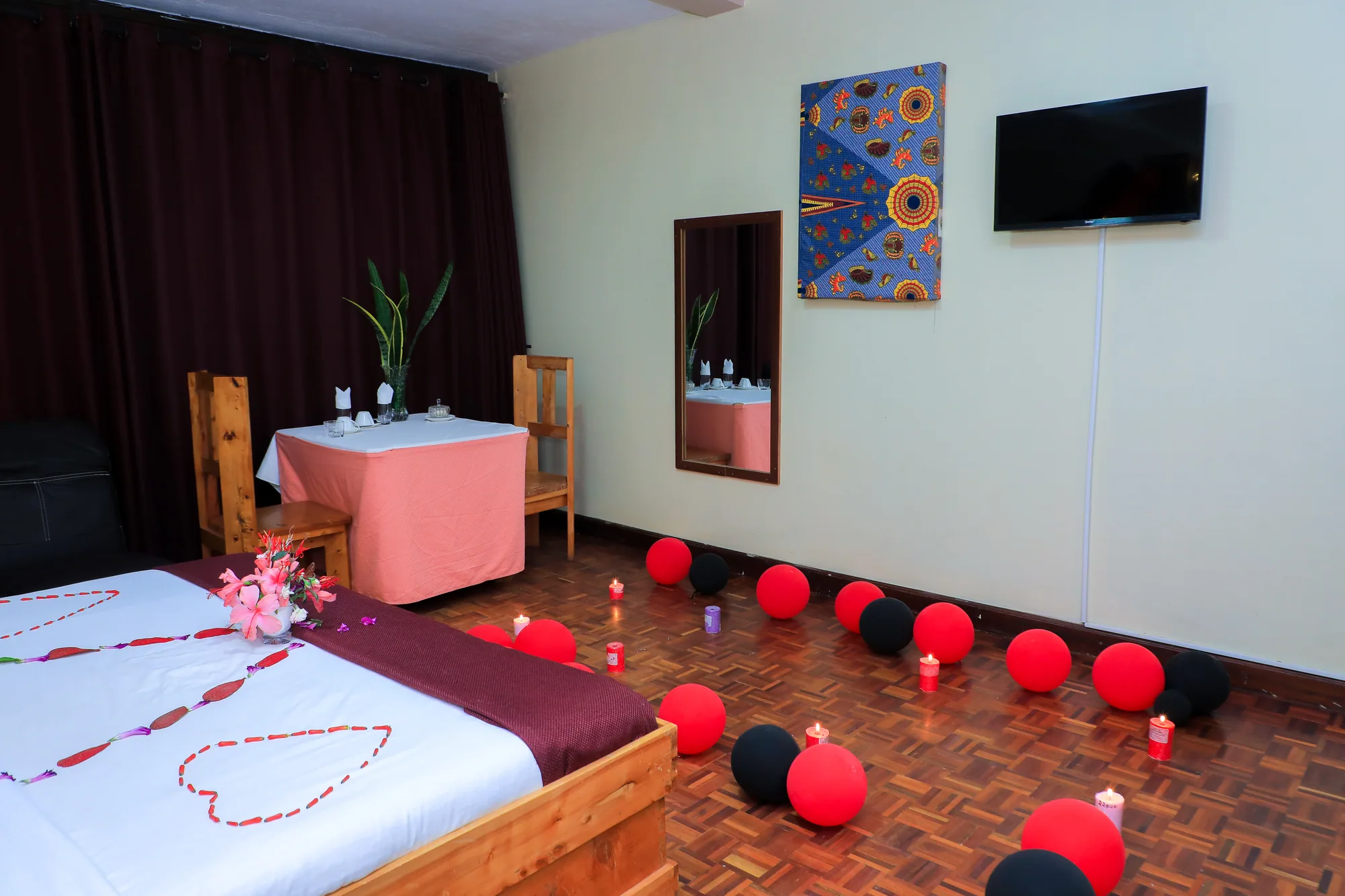 Deluxe Triple Room: room dressed for a celebration with a heart of petals on the bed and balloons on the floor