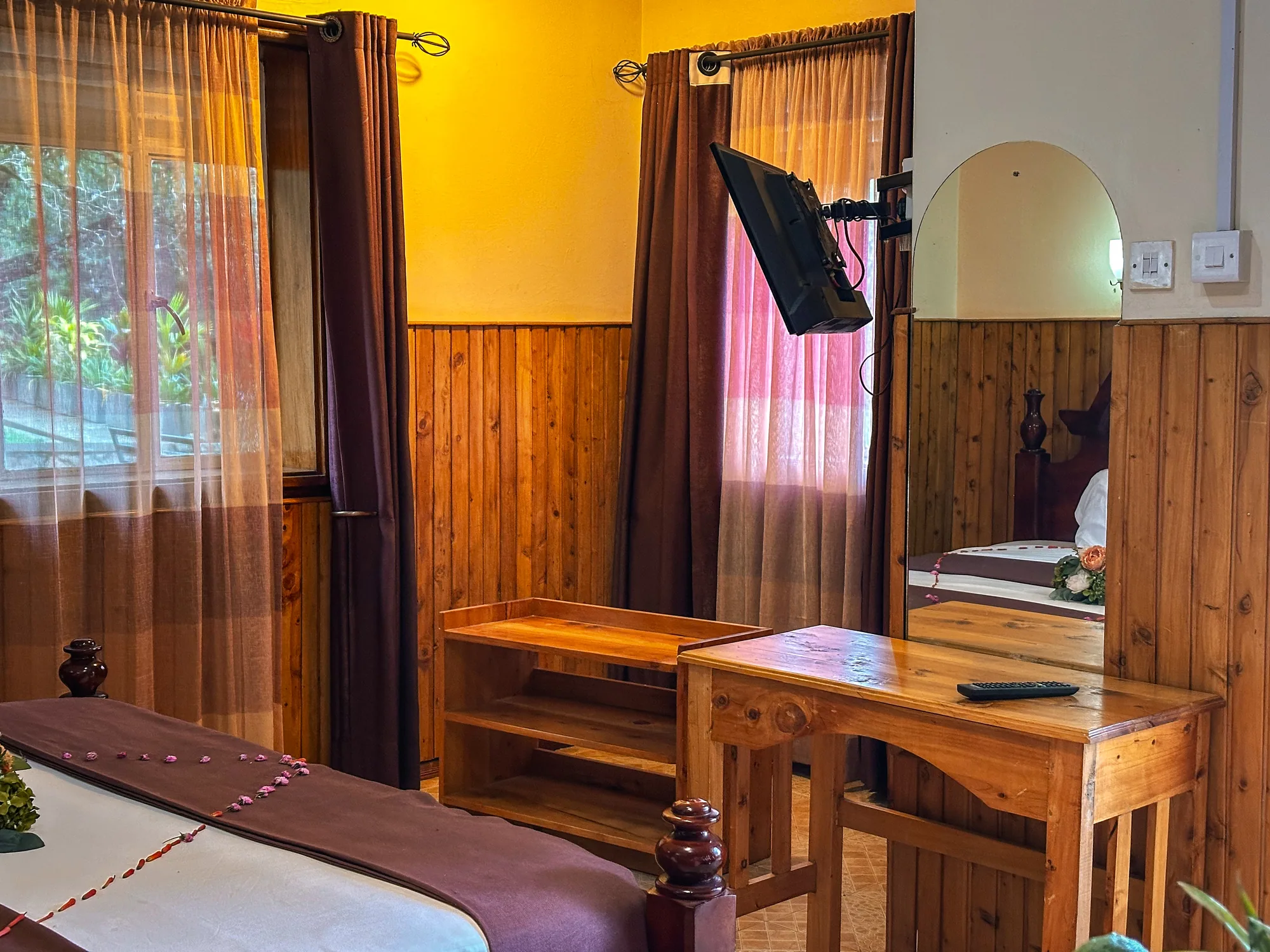 Cottage: panelled room with a bed strewn with petals, a desk and a pink-curtained window