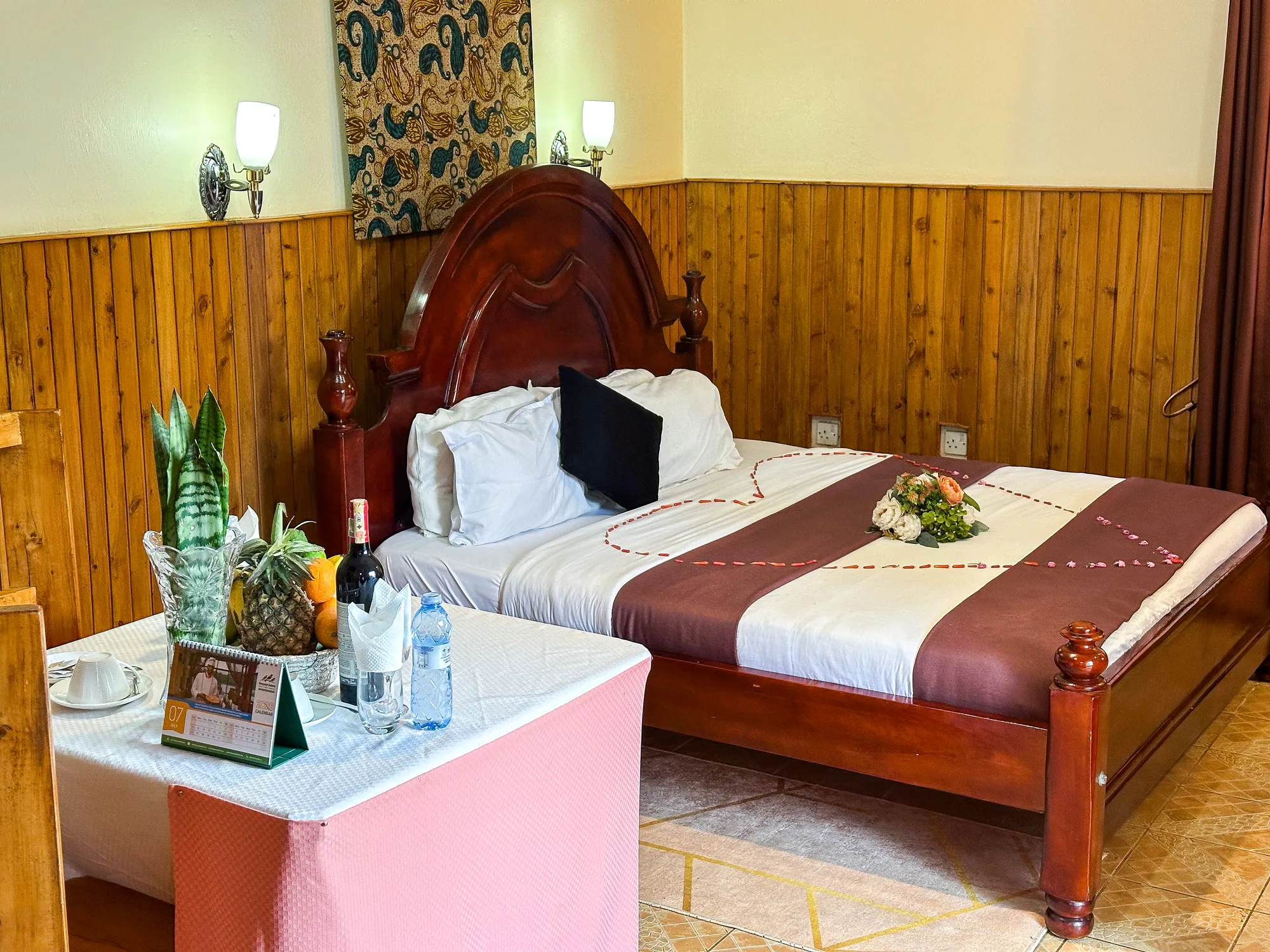 Cottage: carved bed with a welcome table of fruit and wine and flowers on the bedspread