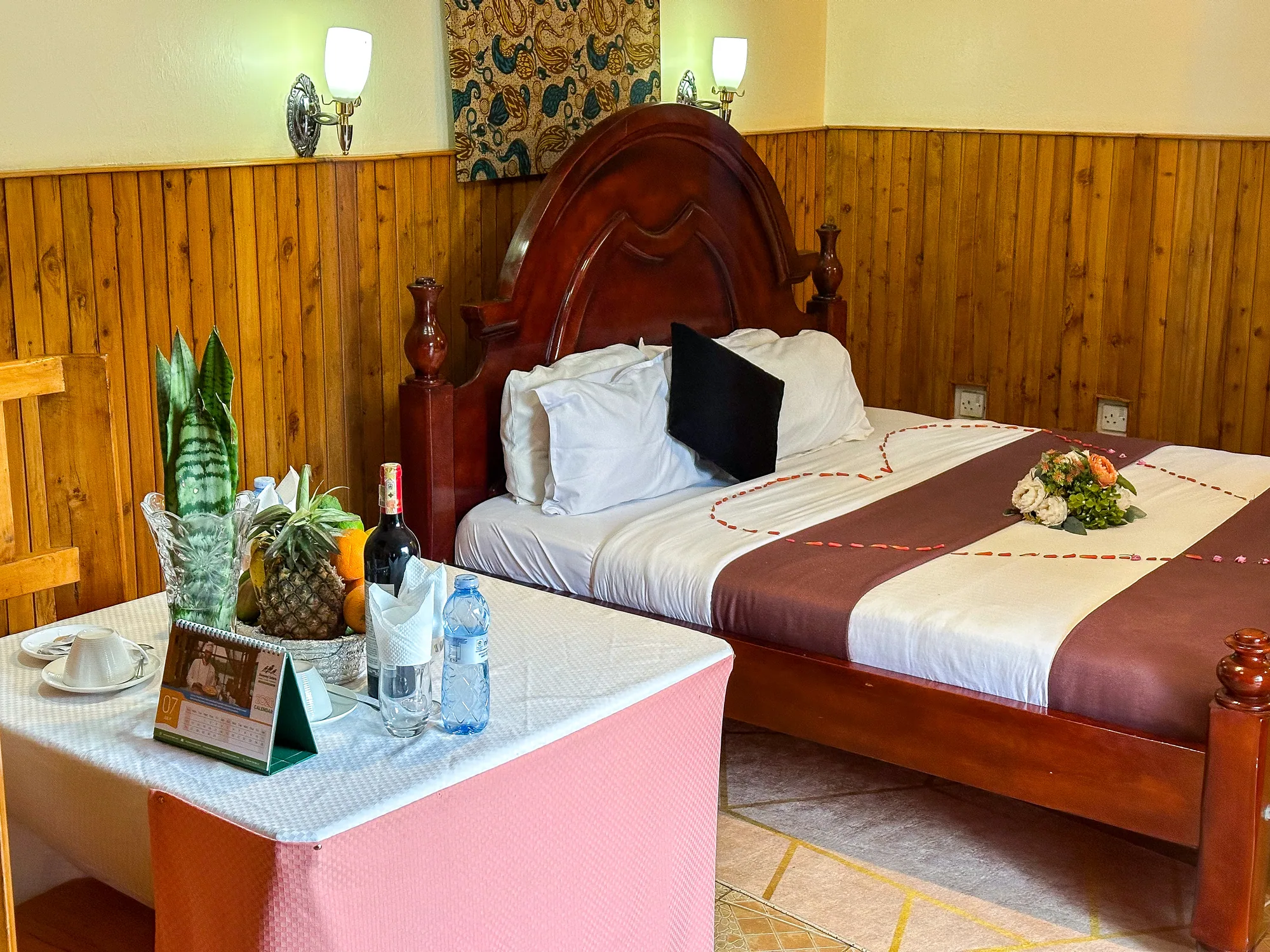 Cottage bedroom with a dark carved wooden bed and a fruit and drinks welcome table