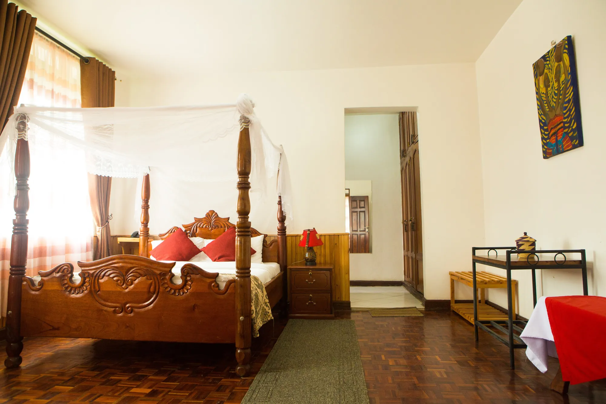 Family Suite: carved four-poster bed with red cushions, the bathroom door open beyond