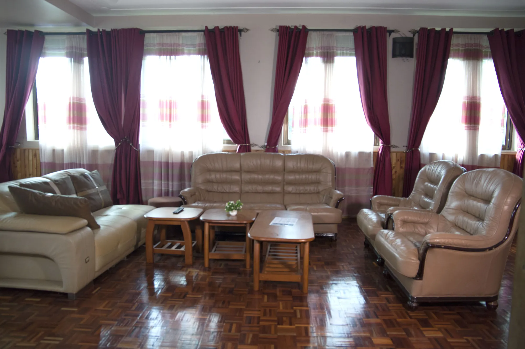 Family Suite: suite lounge with leather and fabric sofas on a parquet floor under maroon-curtained windows