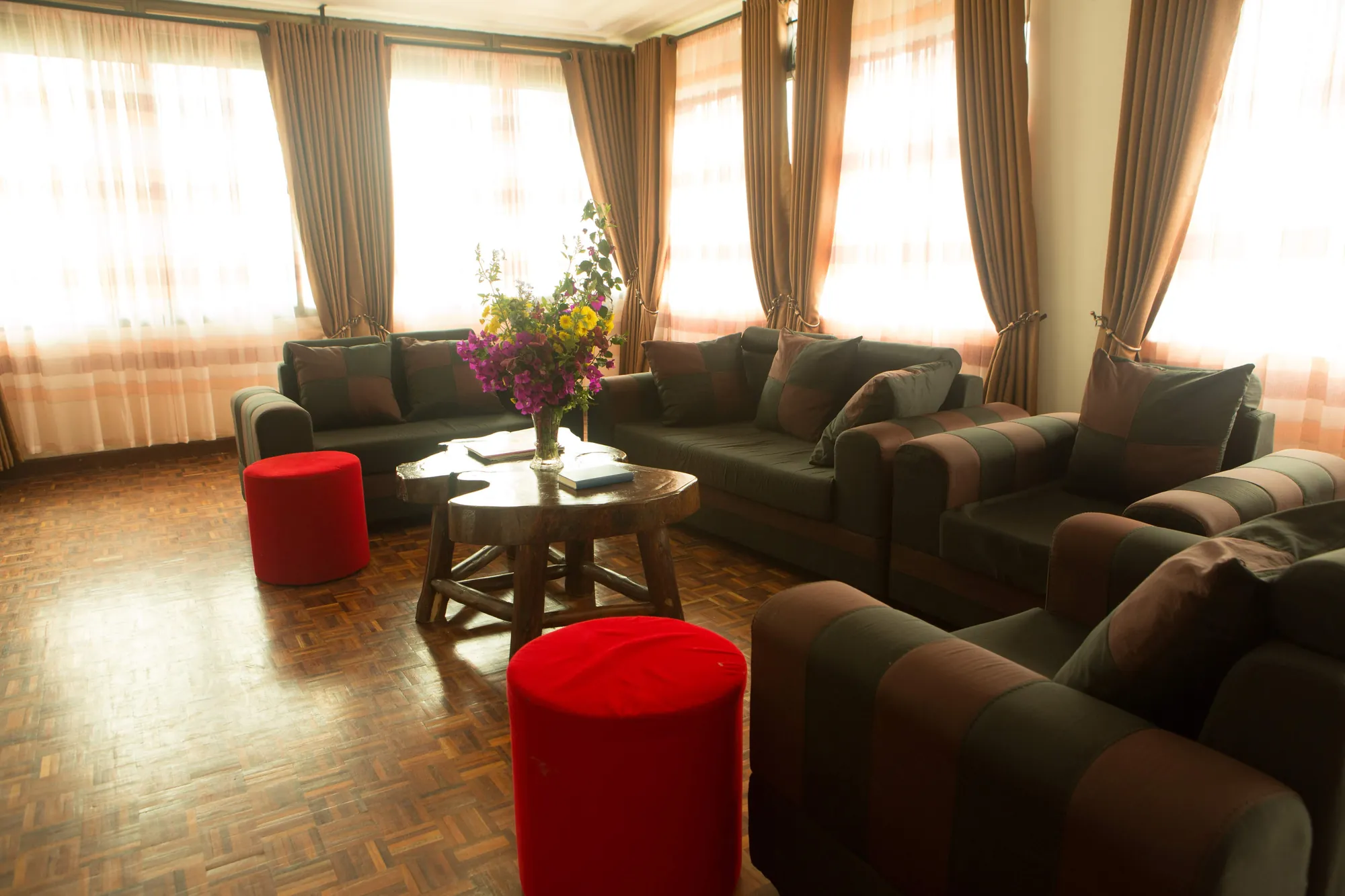 Family Suite: suite sitting room with sofas, red stools and flowers on a low table