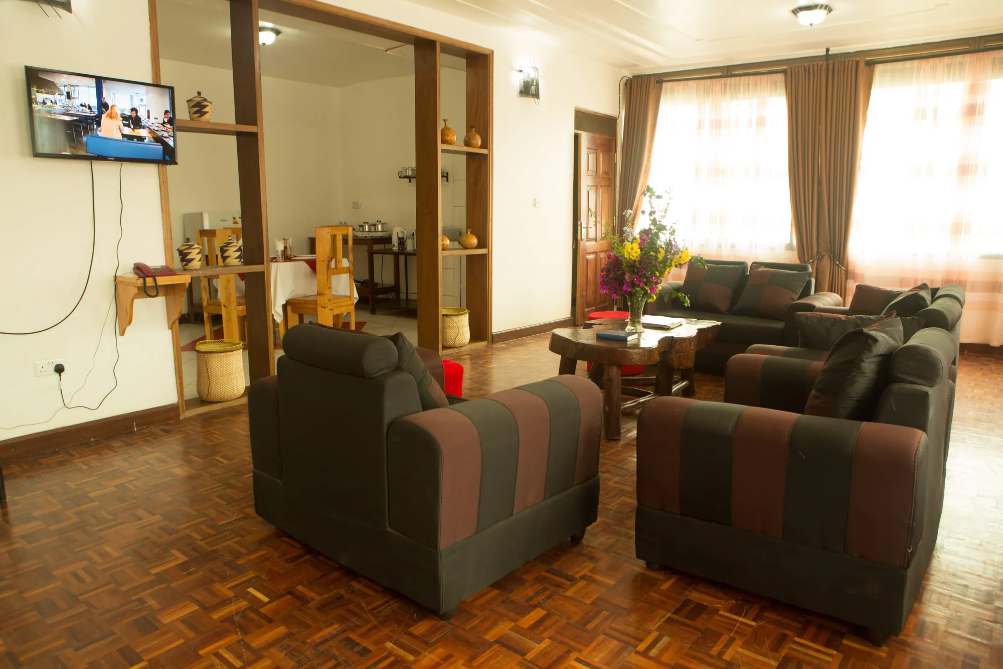 Family Suite: suite lounge with sofas, a wall-mounted television and a shelf unit by the windows