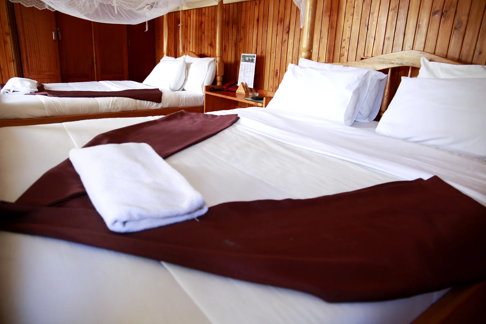 Family Suite: two neatly made beds with white linen and maroon runners in a timber-panelled guest room