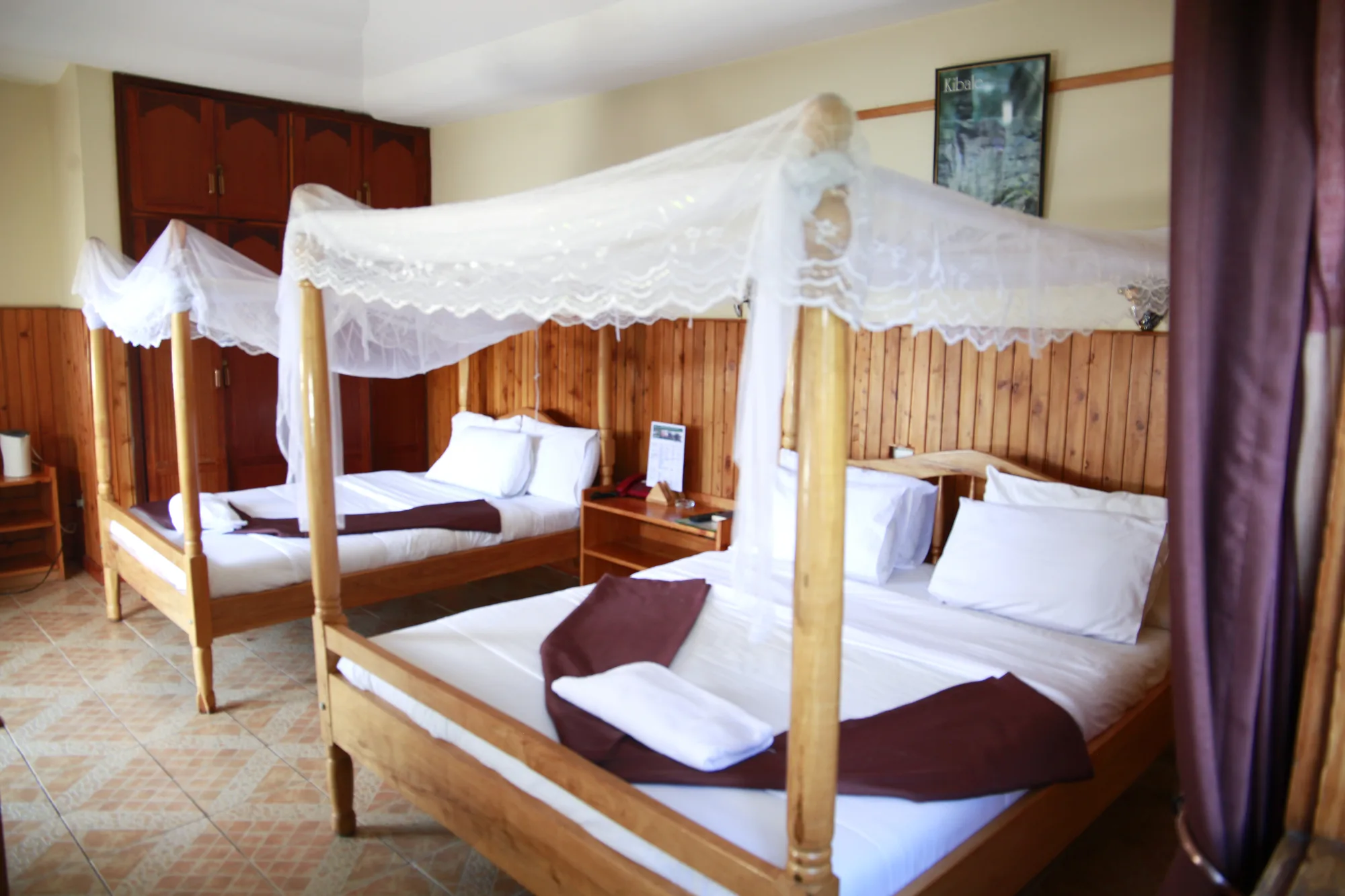 Family Suite: bed with a draped lace mosquito net and folded towels in a timber-panelled guest room