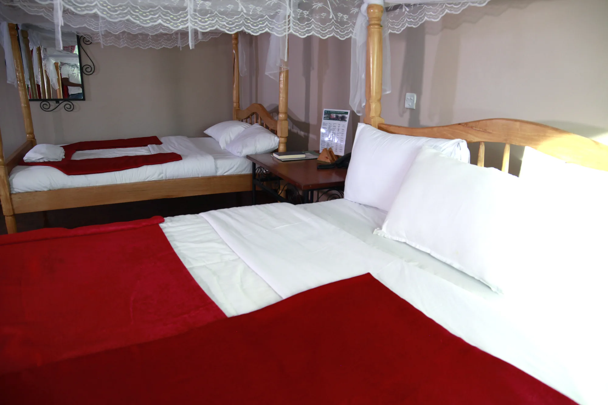 Family Suite: two single beds with white linen and a mosquito net over a red carpeted guest room floor