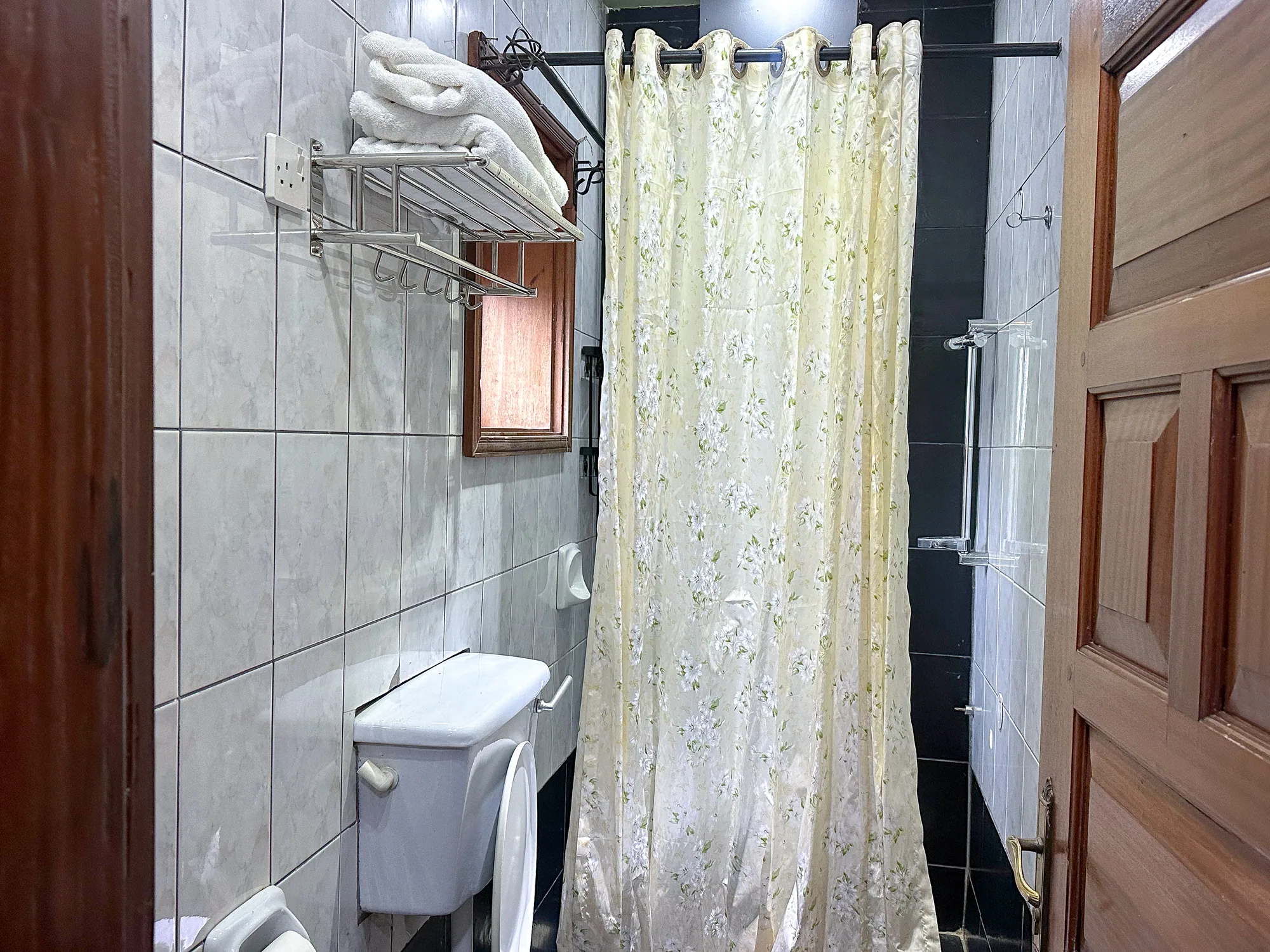 A bathroom with a tiled shower, curtain, hand basin and folded towels on the rail