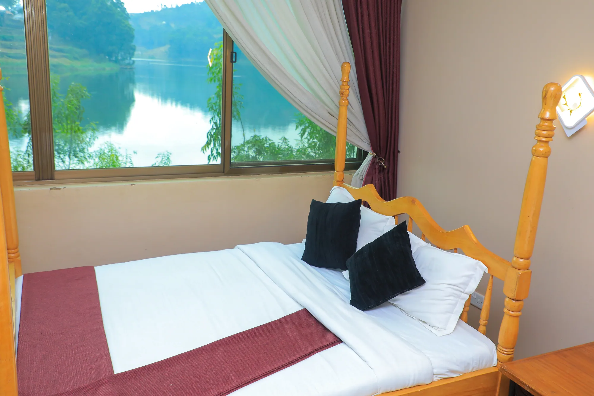 Single Room: single bed with a maroon runner beside a window overlooking the lake