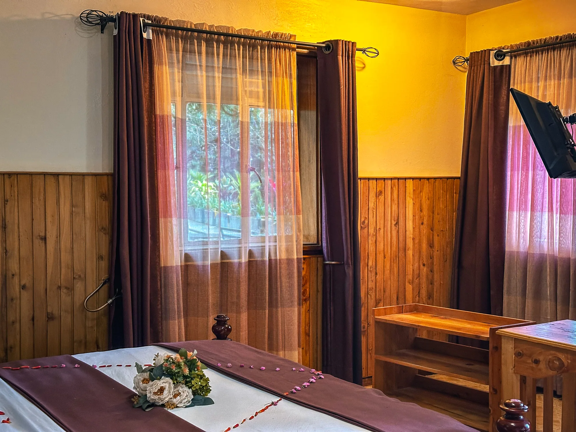 Single Room: single room with a petal-decorated bed, timber panelling and pink curtains