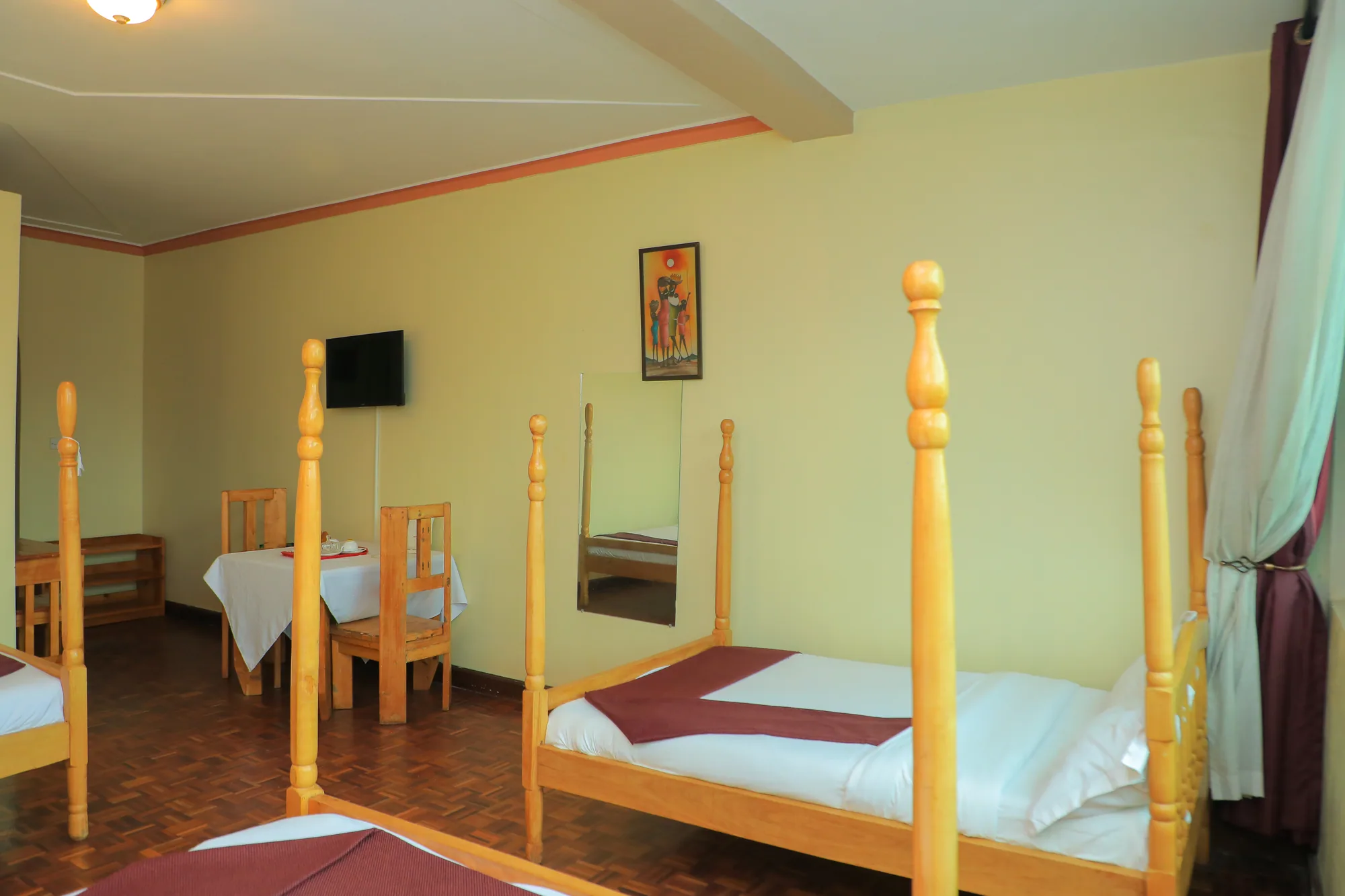 A twin room with two four-poster beds and a small table under a wall-mounted screen